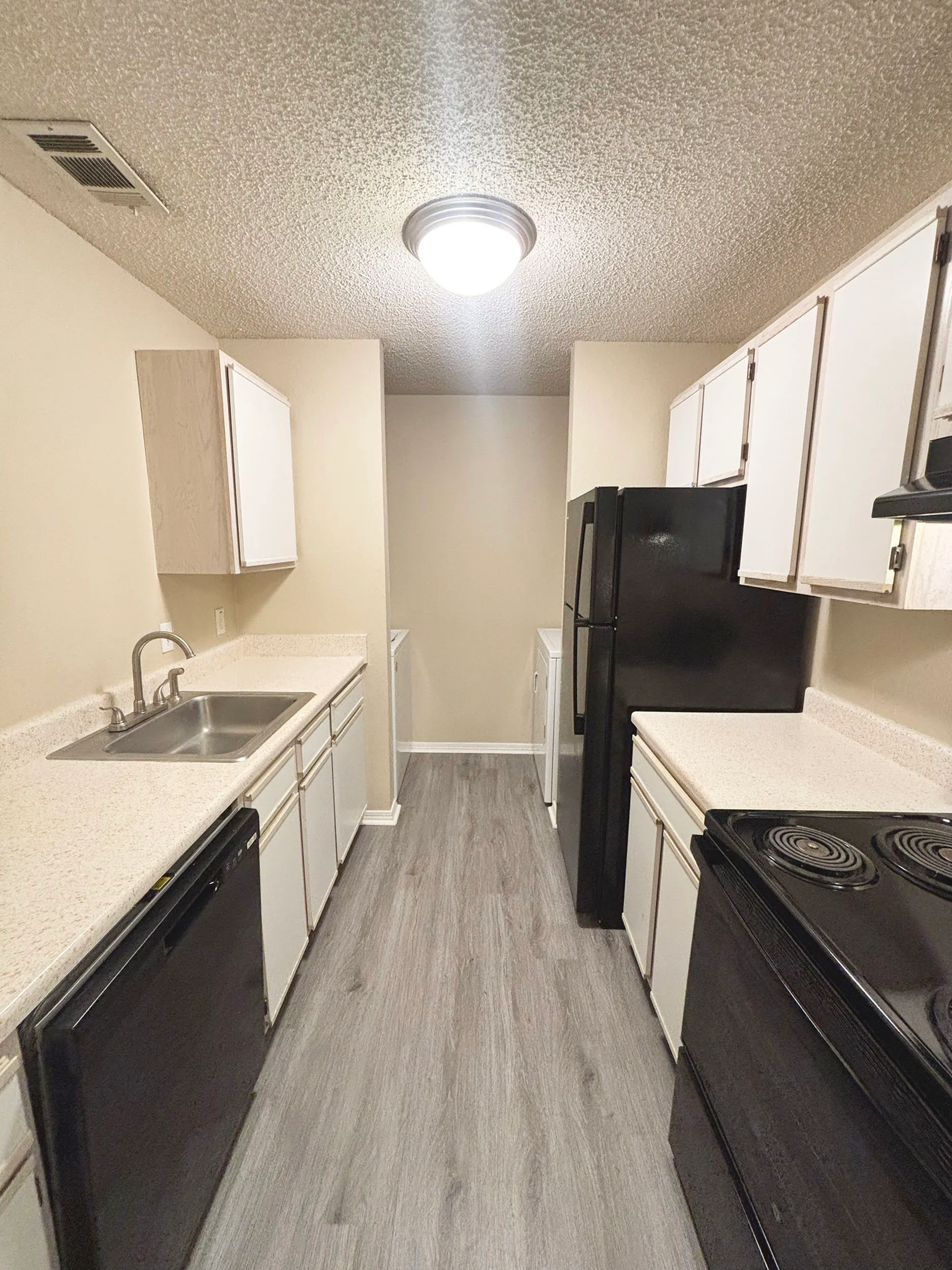 Modern galley kitchen with sleek countertops, stylish cabinetry, and new appliances, offering a cozy and efficient cooking space.