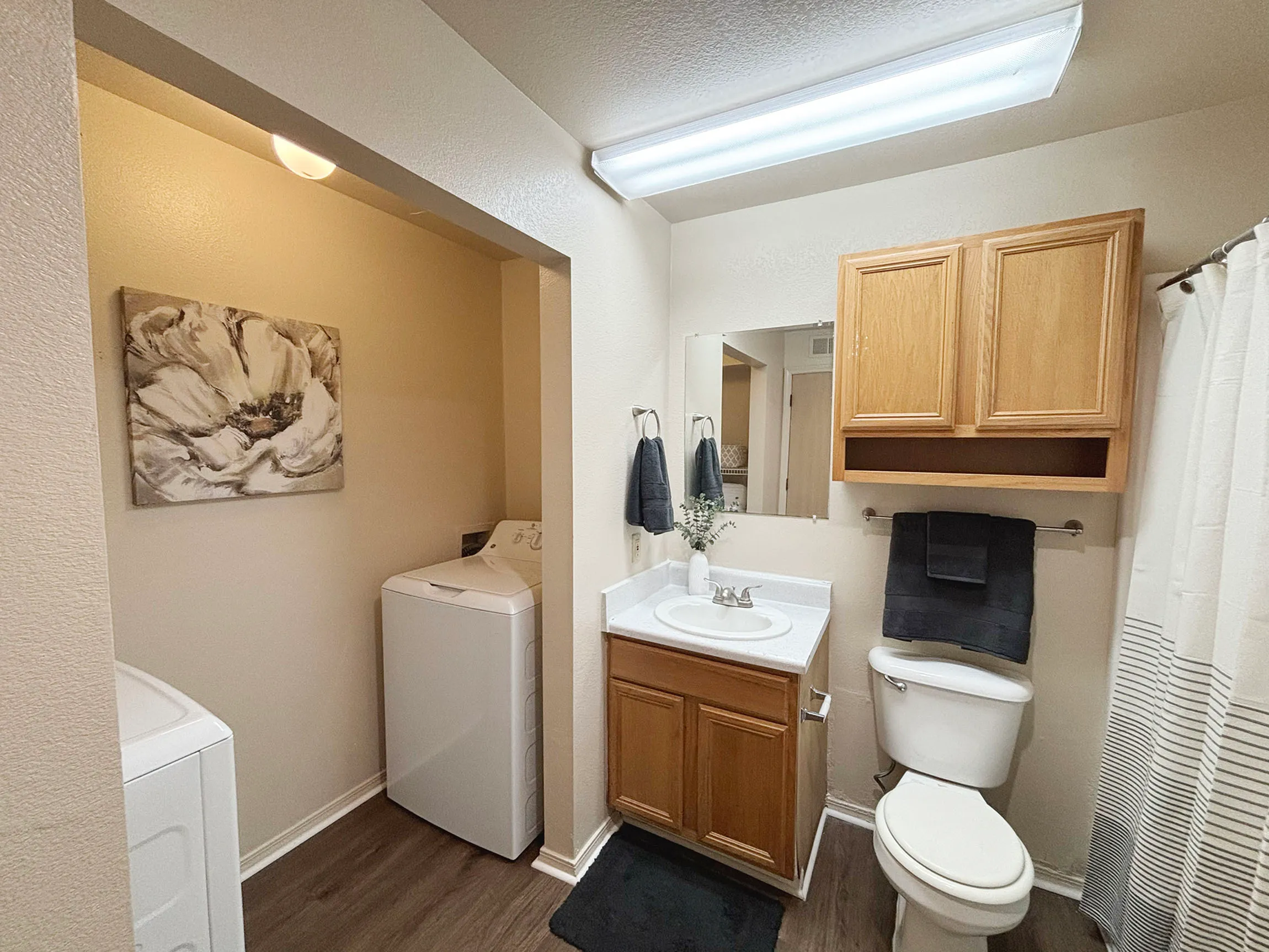 Chic bathroom featuring modern fixtures, ample cabinet storage, and convenient in-unit laundry setup with stylish decor.