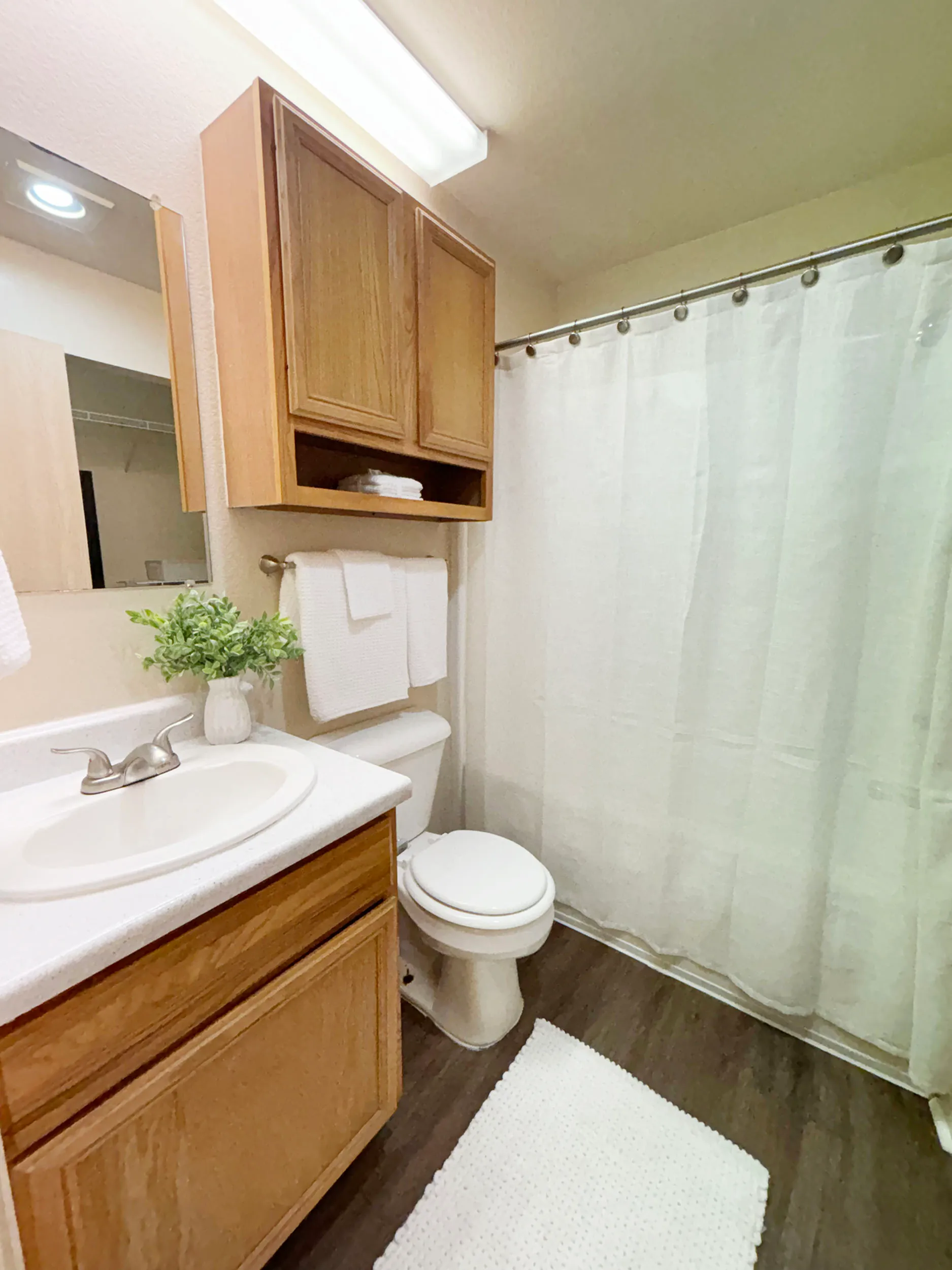 Cozy bathroom with modern amenities, featuring a wooden vanity, white countertop, and elegant shower curtain.