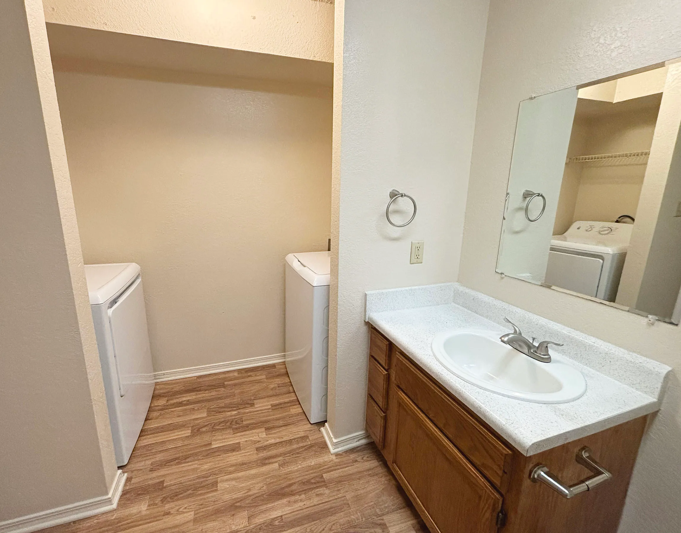 Charming laundry area with washer and dryer adjacent to a sleek bathroom vanity, showcasing modern design and functionality.