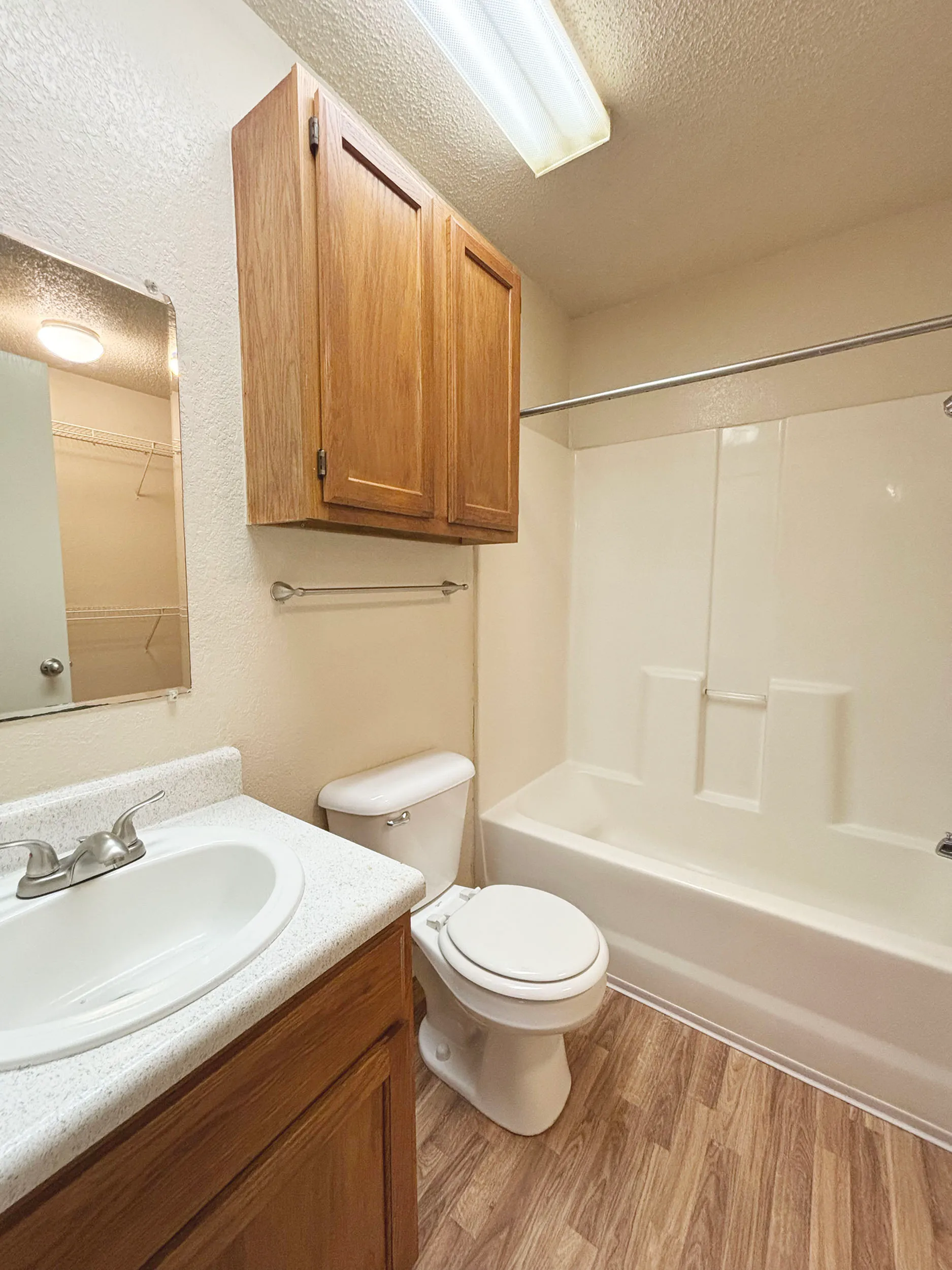 Modern bathroom featuring elegant wooden cabinetry, shiny fixtures, and a clean white bathtub with a shower.