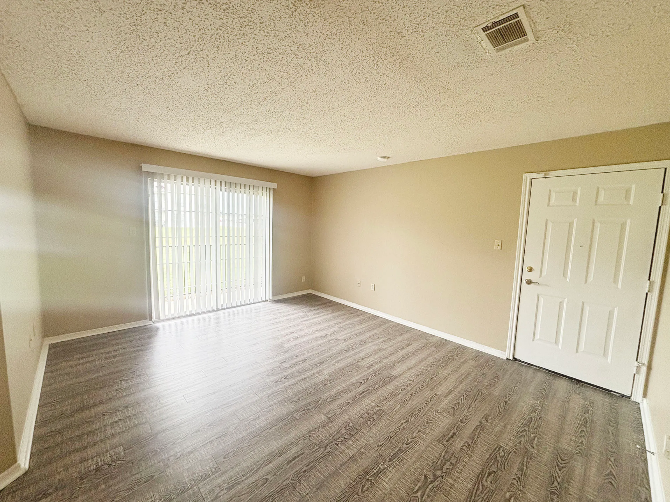 Bright and spacious living room with modern wood flooring, large sliding doors, and ample natural light.