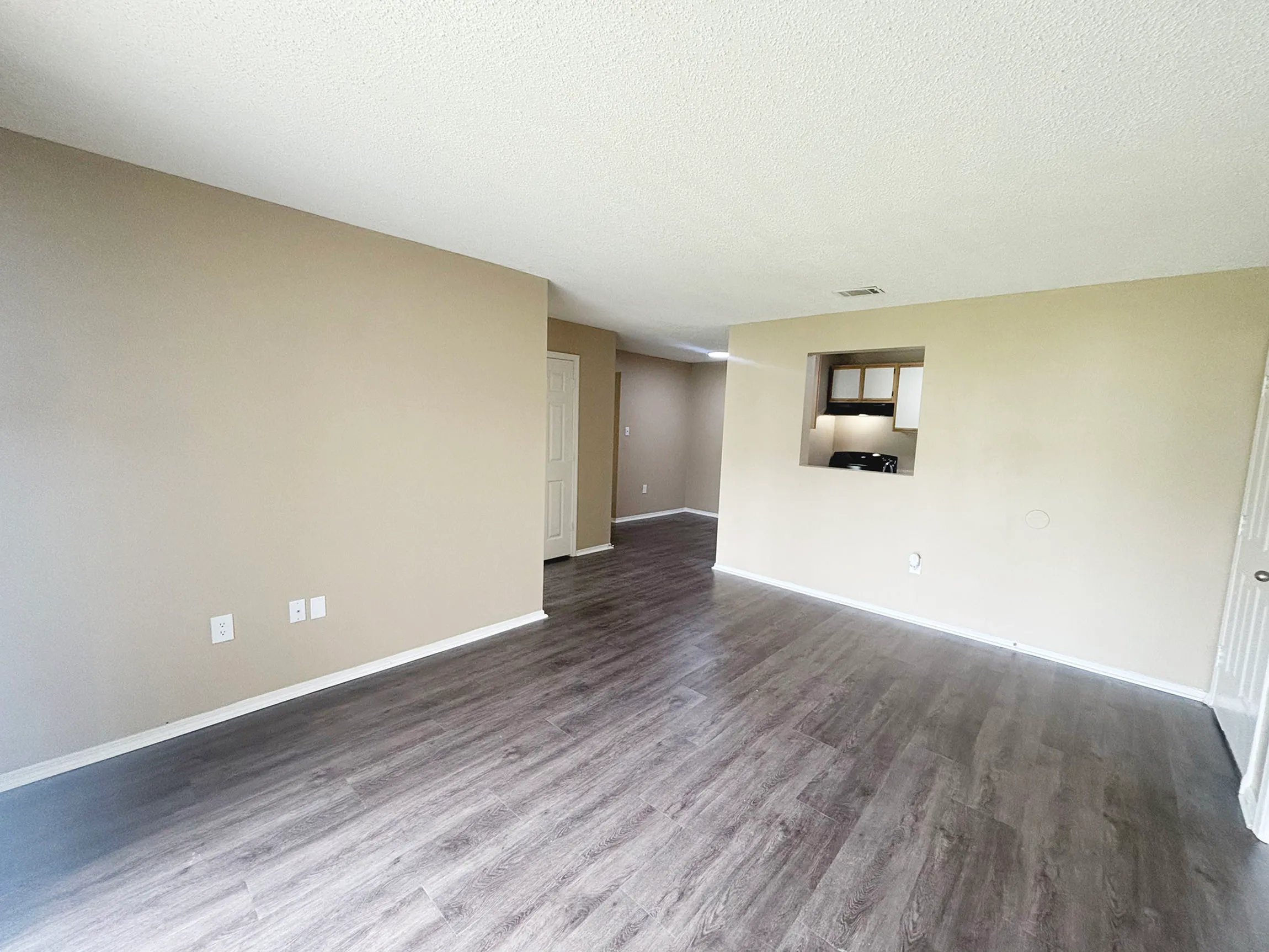Bright, open-concept living area with elegant hardwood flooring and neutral wall tones, perfect for personalization and modern living.