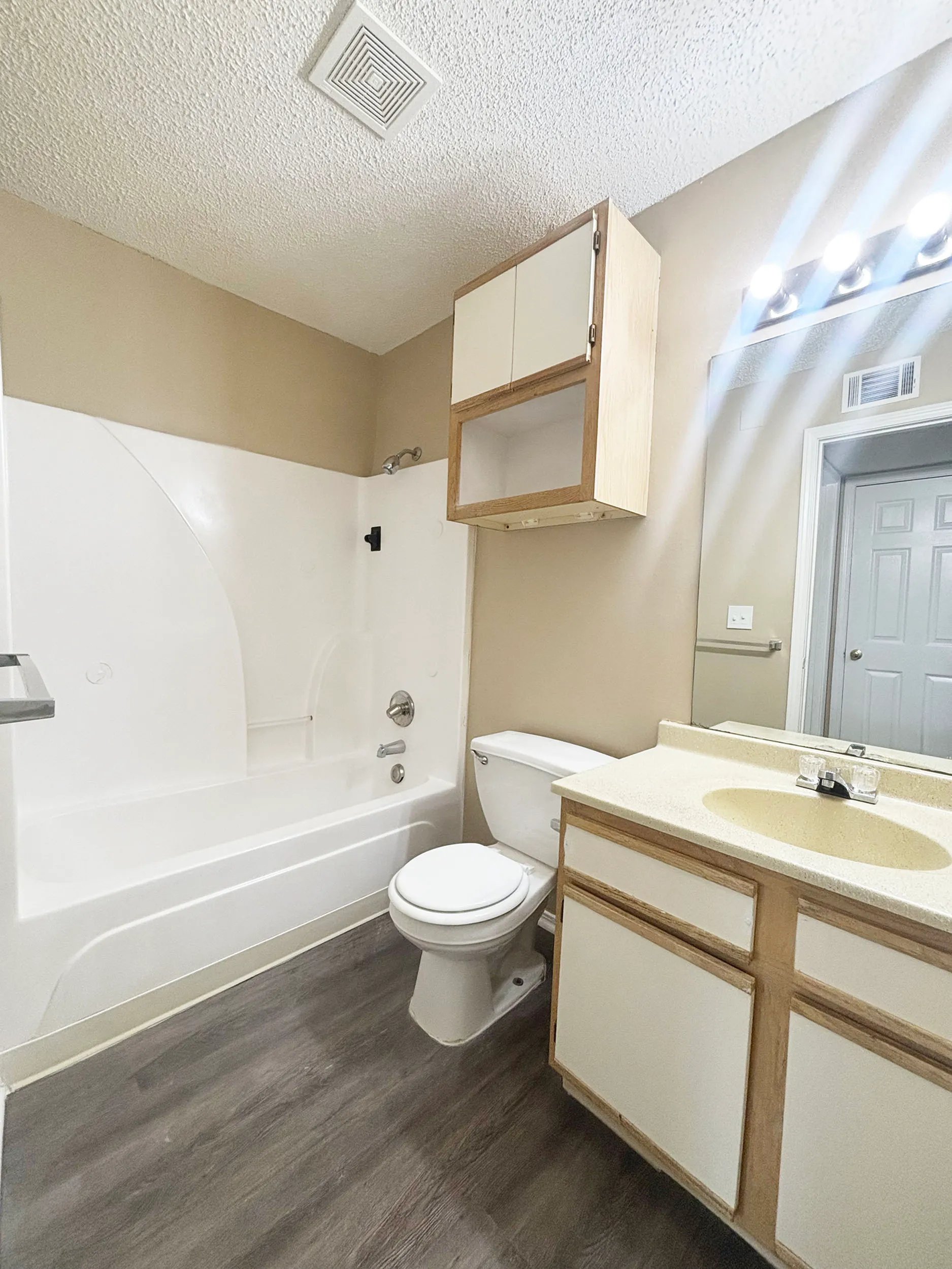 Modern bathroom with sleek fixtures, elegant lighted vanity, and stylish wood flooring.