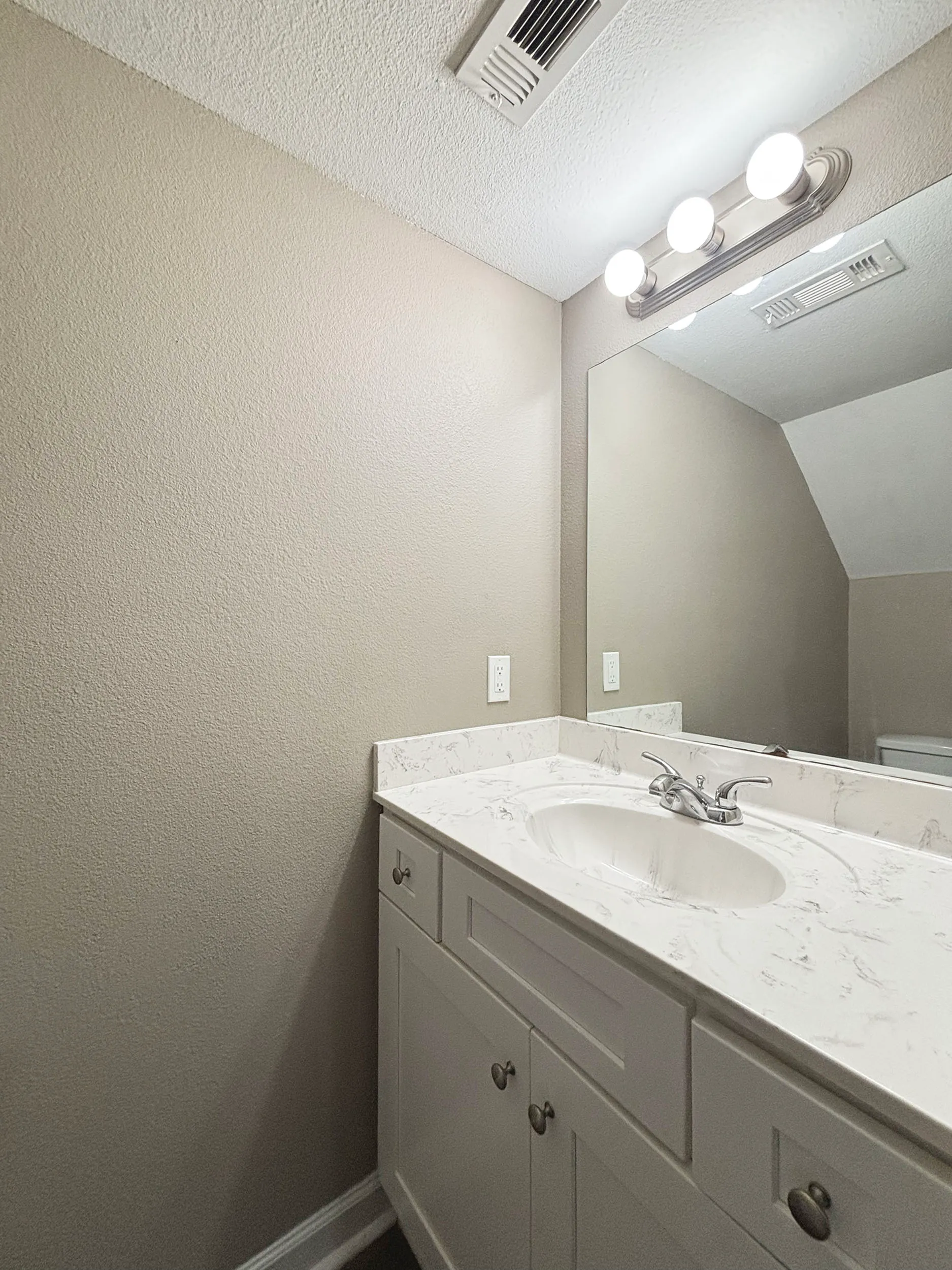 Elegant bathroom featuring a sleek marble vanity with modern lighting and a large mirror.