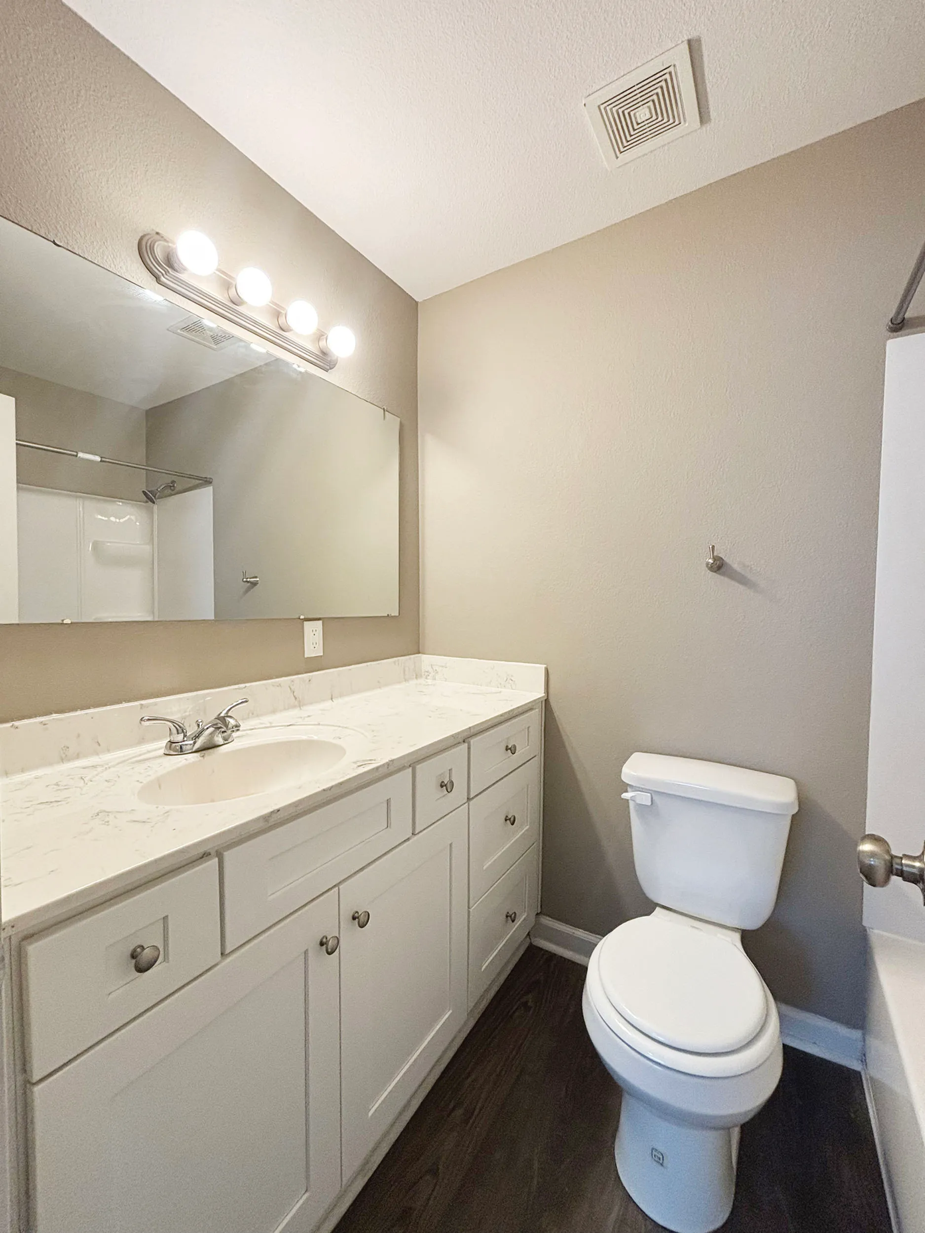 Modern bathroom with elegant vanity, marble countertop, and well-lit mirror.