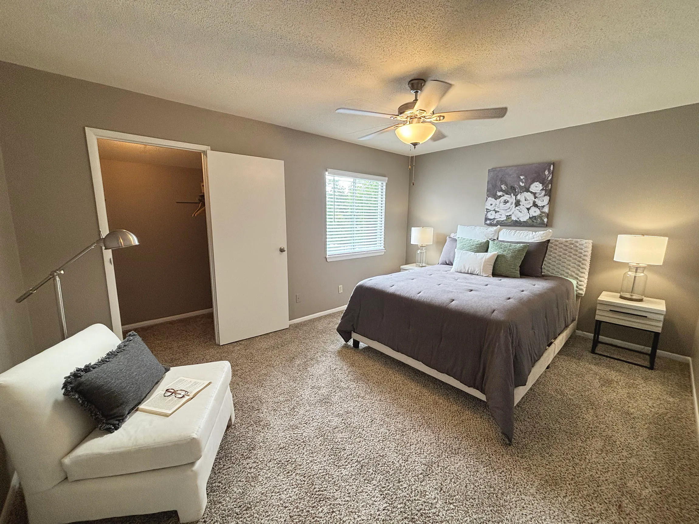 Bright and cozy bedroom with plush carpet, modern decor, and ample natural light, featuring a comfortable seating area and spacious walk-in closet.