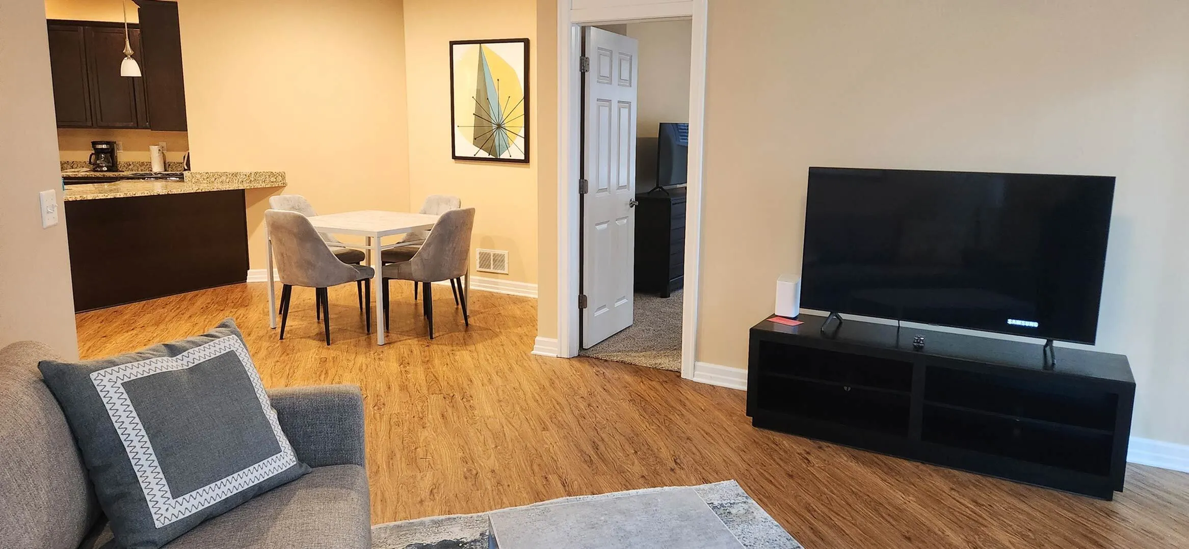 Inviting open-concept living space with hardwood floors, modern dining area, and cozy lounge featuring a large TV.