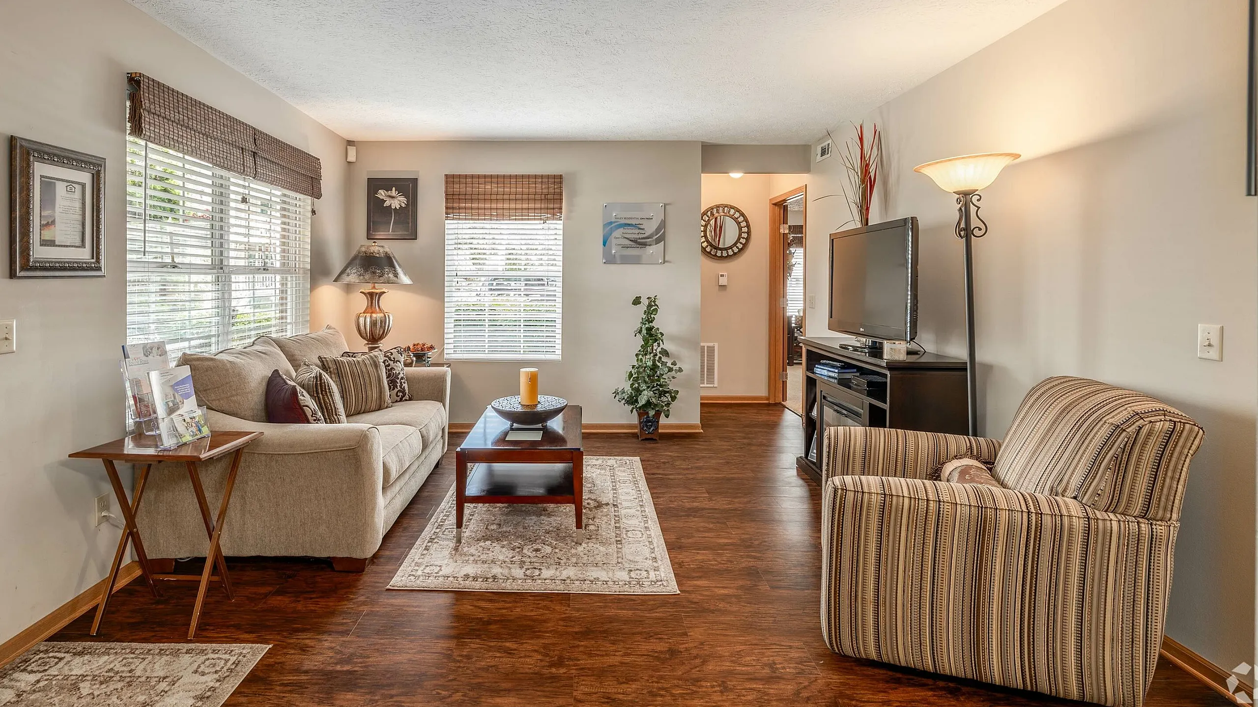 Inviting living room with warm tones, featuring a cozy sofa, elegant armchair, and large windows for ample natural light.