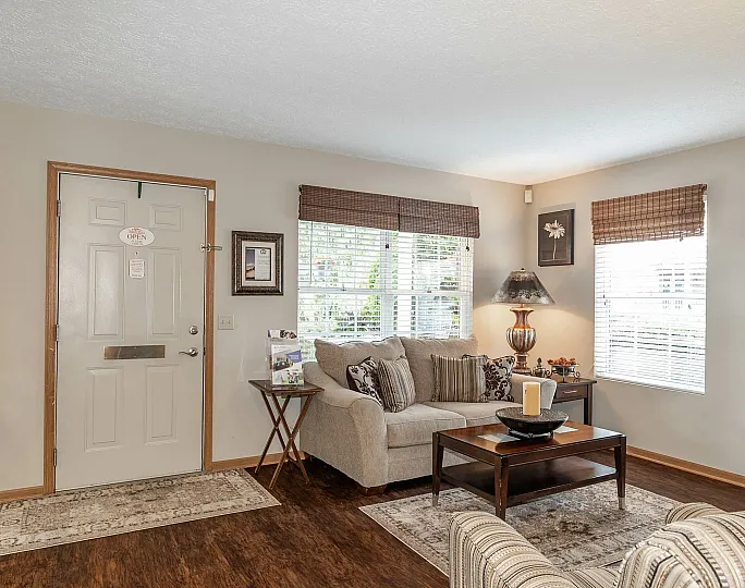 Cozy and inviting living room with elegant decor, featuring a comfortable sofa, stylish table lamp, and warm wooden flooring.