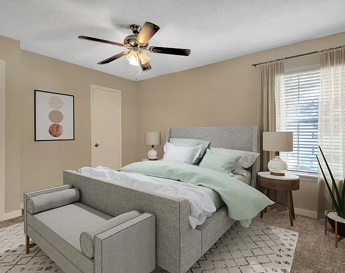 Inviting bedroom with a sleek grey bed, elegant decor, and ample natural light from a large window.