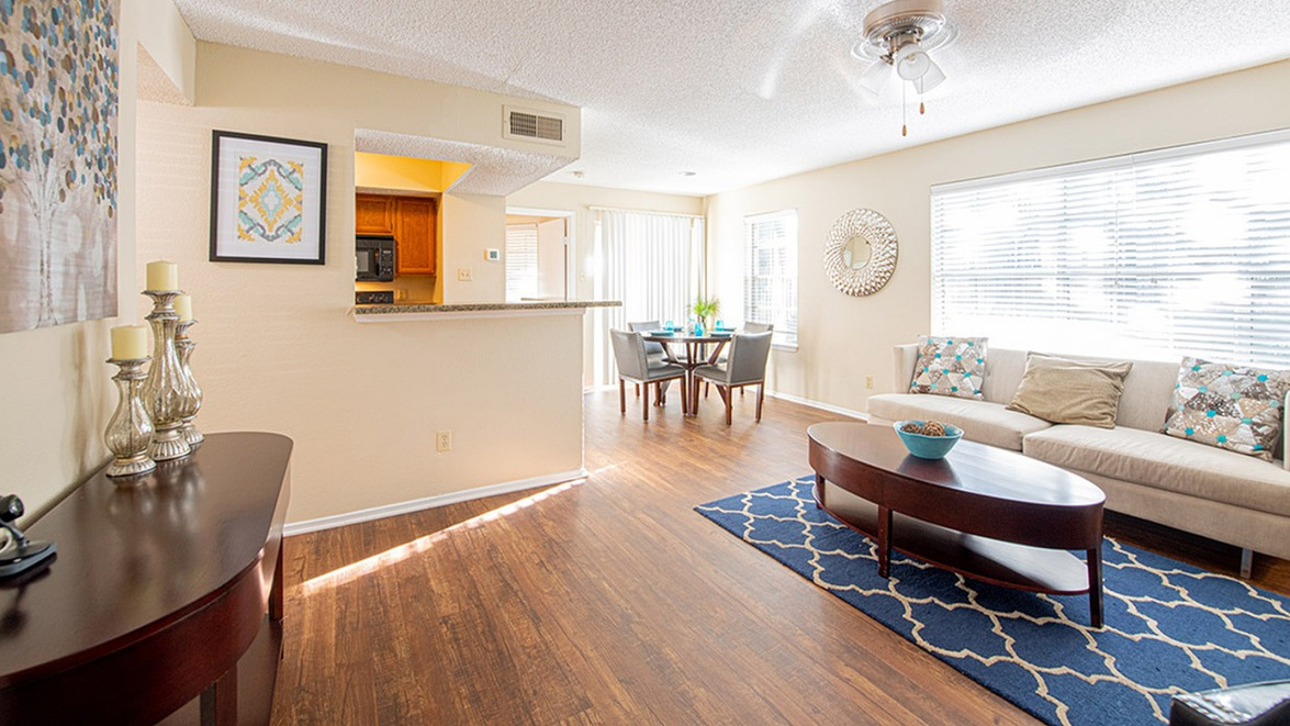 Bright and inviting open-concept living space featuring elegant wood flooring, cozy seating area, and a stylish dining nook by large windows.
