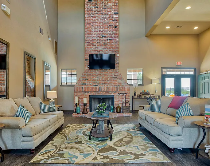 Inviting living room with high ceilings, cozy sofas, and a striking brick fireplace creating a warm, elegant atmosphere.