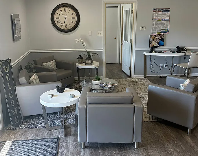 Welcoming apartment lobby with stylish gray seating, a large clock, and a modern workspace.