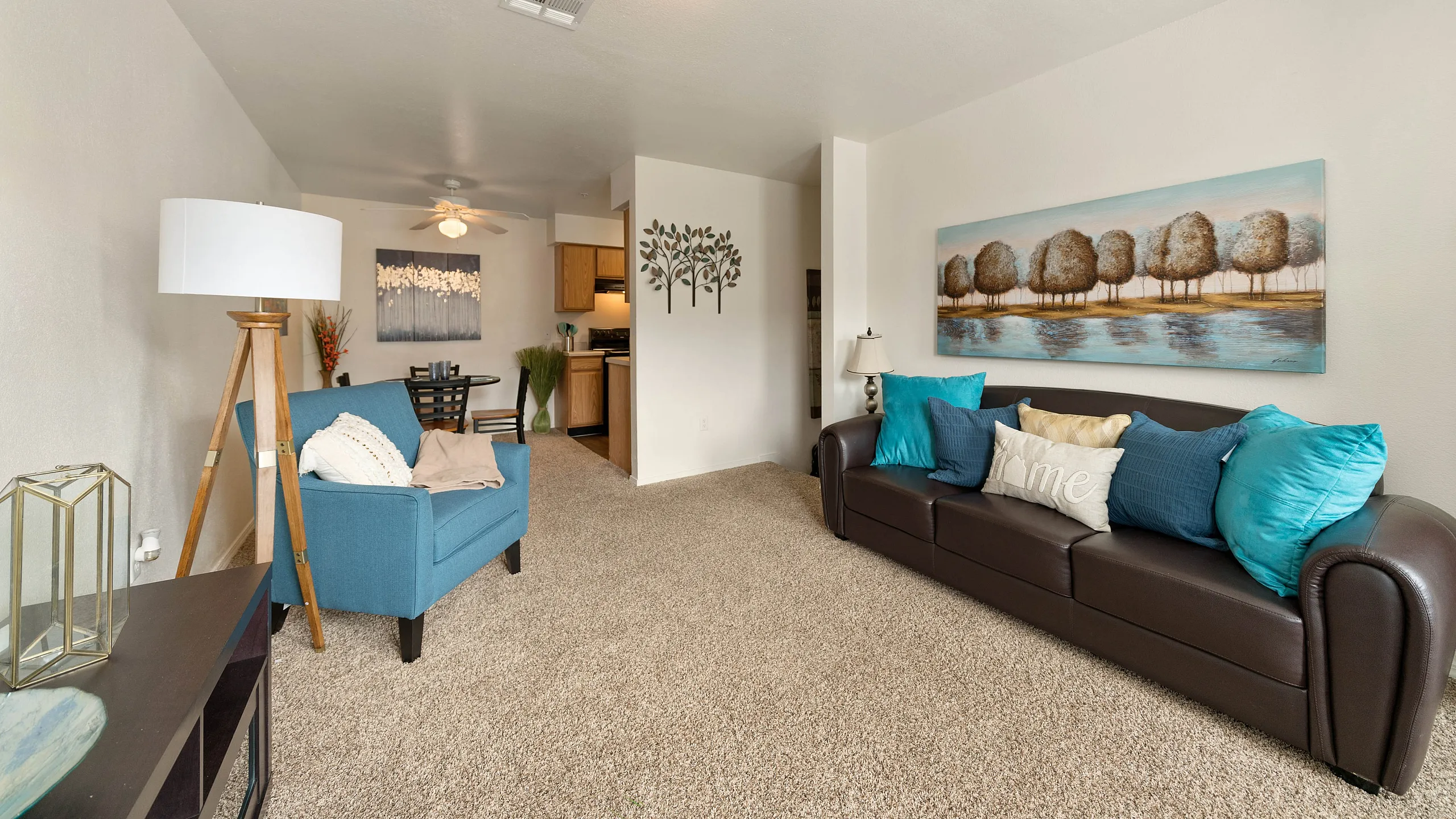 Inviting living room with cozy seating, vibrant cushions, and modern decor, flowing into an intimate dining area and compact kitchen.
