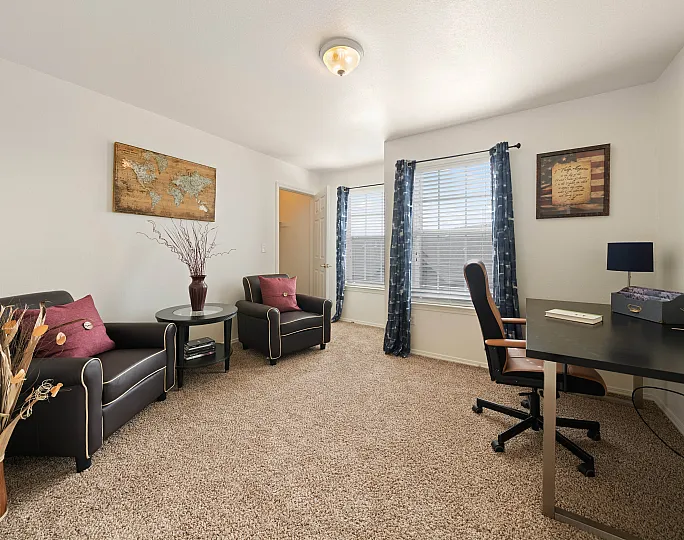 Elegant home office with comfortable seating, stylish decor, and natural light creating a serene and productive workspace.