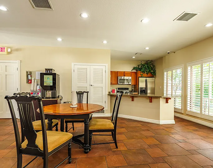Inviting open-concept kitchen and dining area featuring cozy seating, warm wooden cabinetry, and abundant natural light streaming through elegant plantation shutters.
