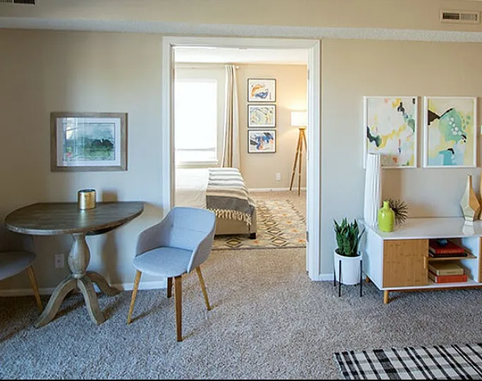 Inviting apartment interior with a cozy dining area, contemporary decor, and view into two stylishly furnished bedrooms.