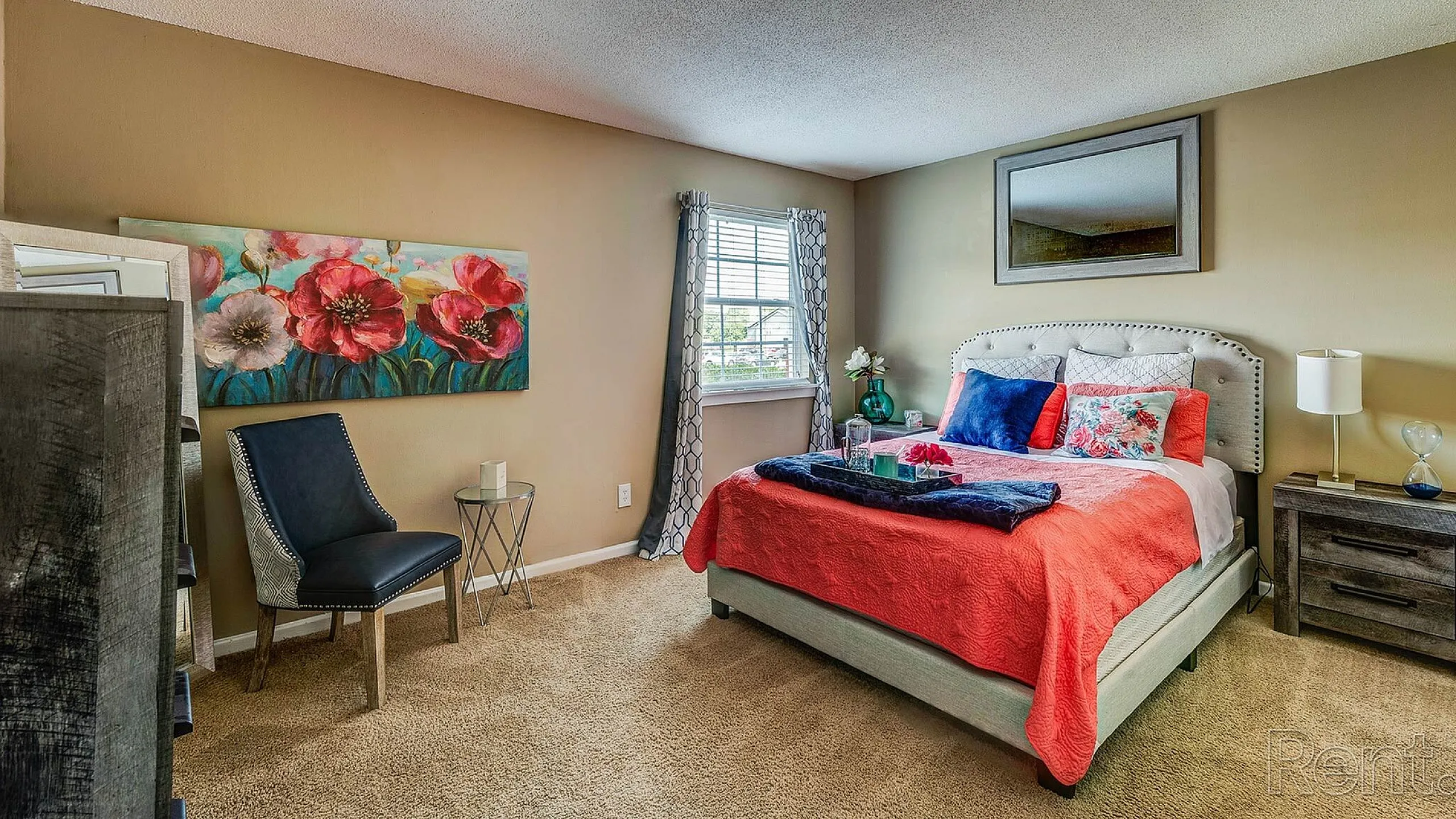 Chic and cozy bedroom with vibrant floral artwork, plush bedding, and a sunlit window offering a serene retreat.
