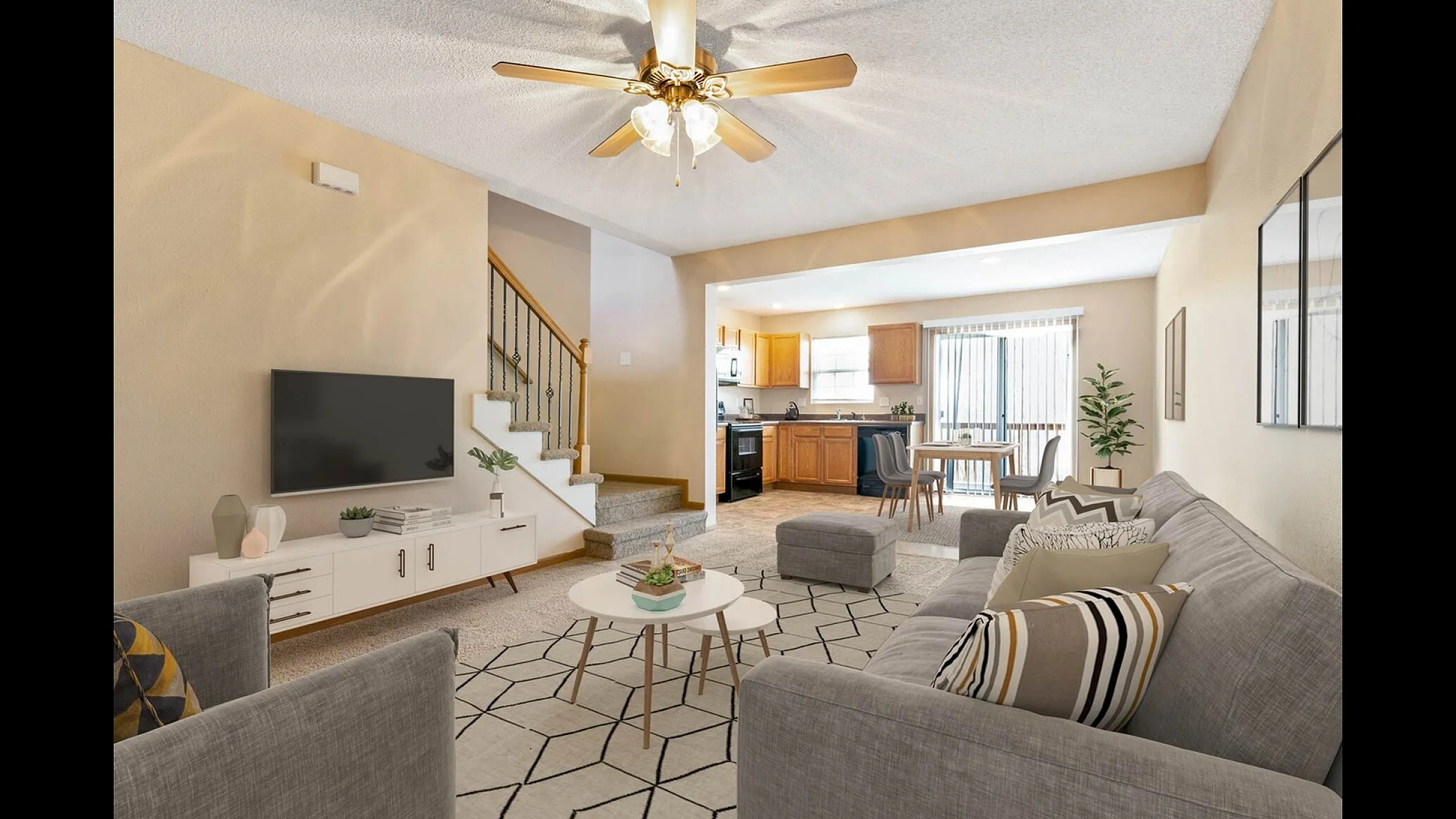 Inviting open-concept living area with modern decor, cozy seating, elegant ceiling fan, and adjacent stylish kitchen.