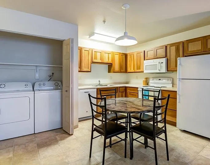 Bright kitchen with wooden cabinets, modern appliances, and in-unit laundry, plus a stylish dining area.