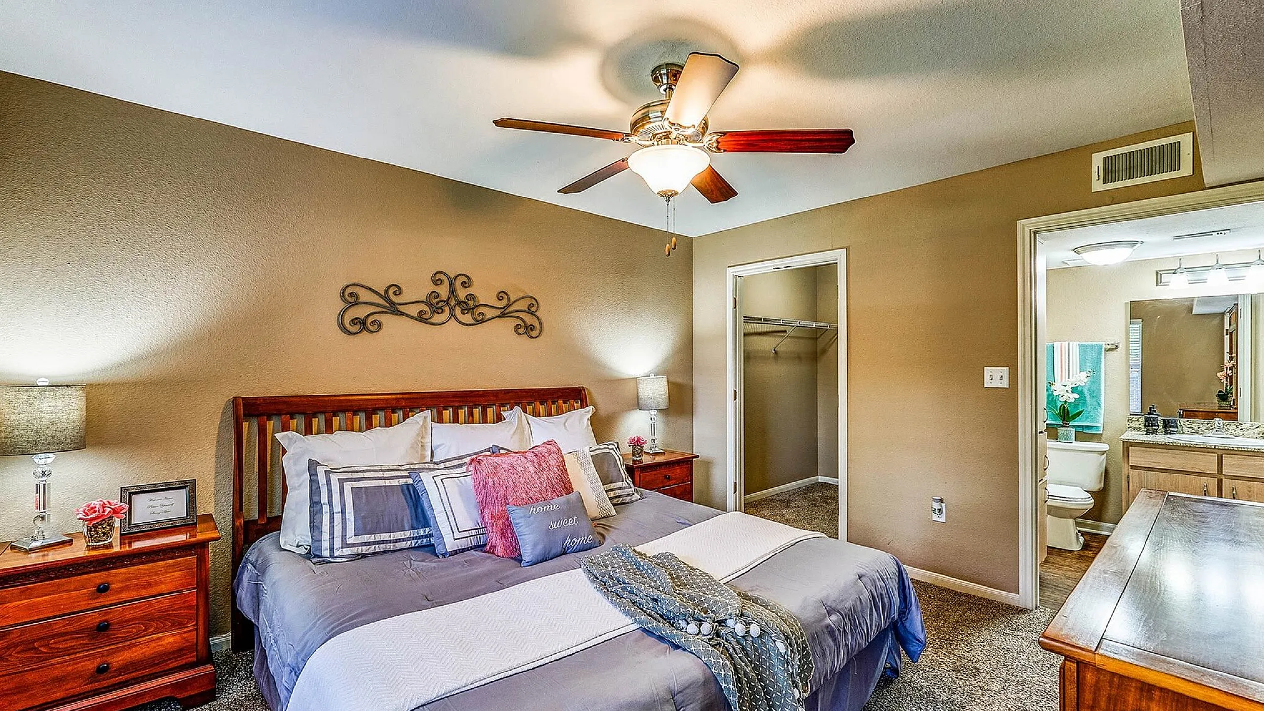 Inviting bedroom with elegant decor, featuring a plush bed, stylish ceiling fan, and direct access to a modern en-suite bathroom.