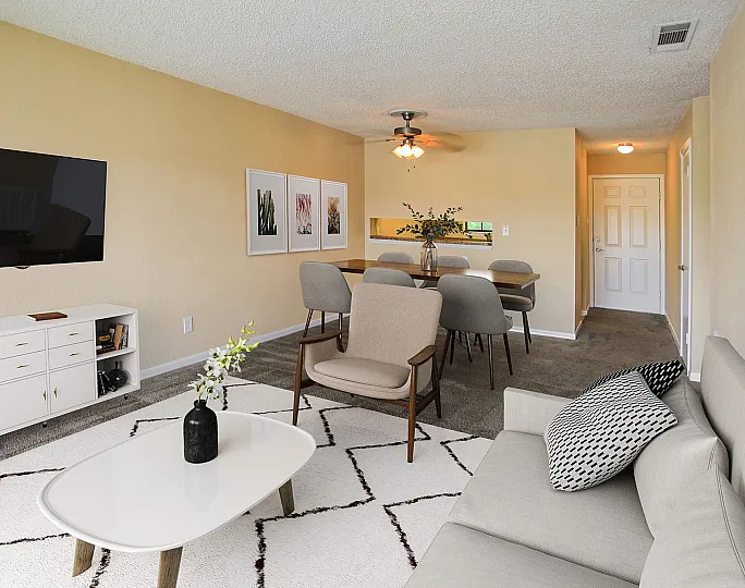 Inviting living and dining area with modern decor, featuring a sleek TV setup, cozy armchairs, and a stylish dining table perfect for entertaining.