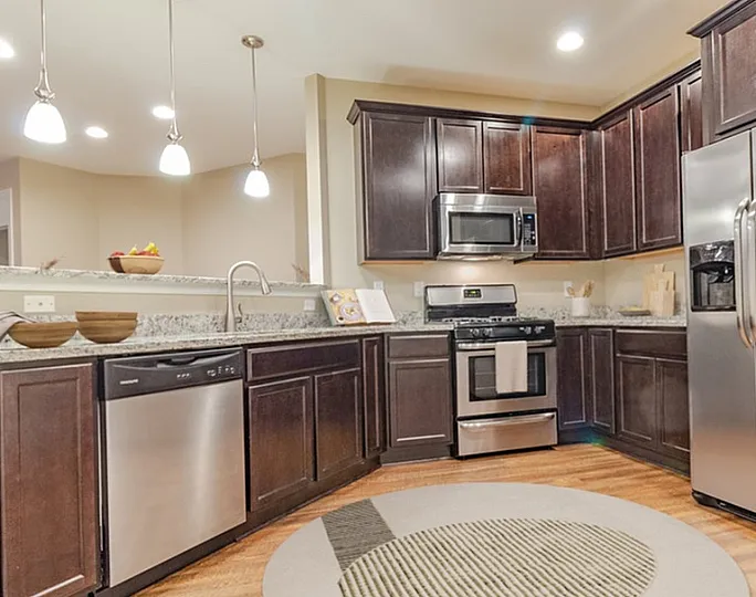 Elegant modern kitchen with dark wood cabinets, stainless steel appliances, and ambient pendant lighting.
