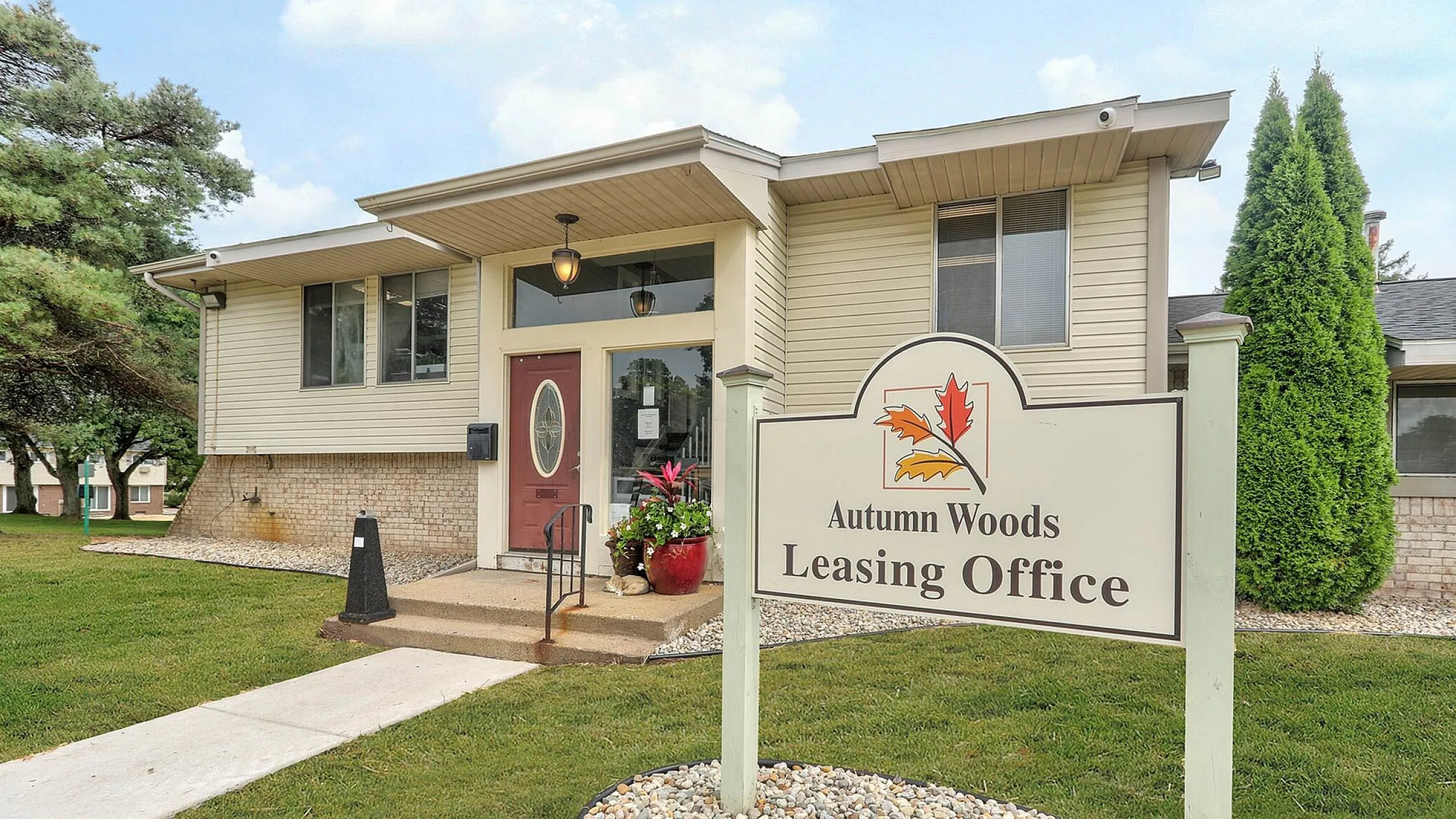 Inviting entrance to Autumn Woods Leasing Office, nestled in a serene setting with lush greenery and a welcoming pathway.