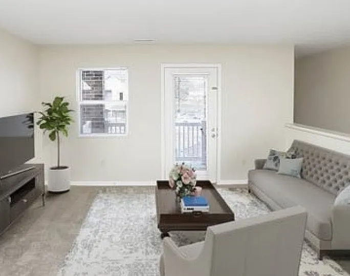 Luxurious living room with plush gray sofas, modern TV setup, and natural light flooding through large windows.