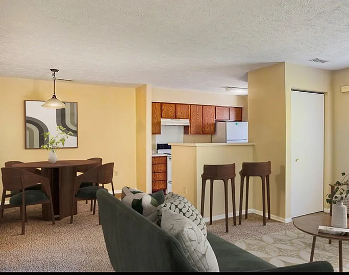 Inviting open-concept living room and dining area with cozy seating and modern decor, leading into a functional kitchen with wooden cabinetry.