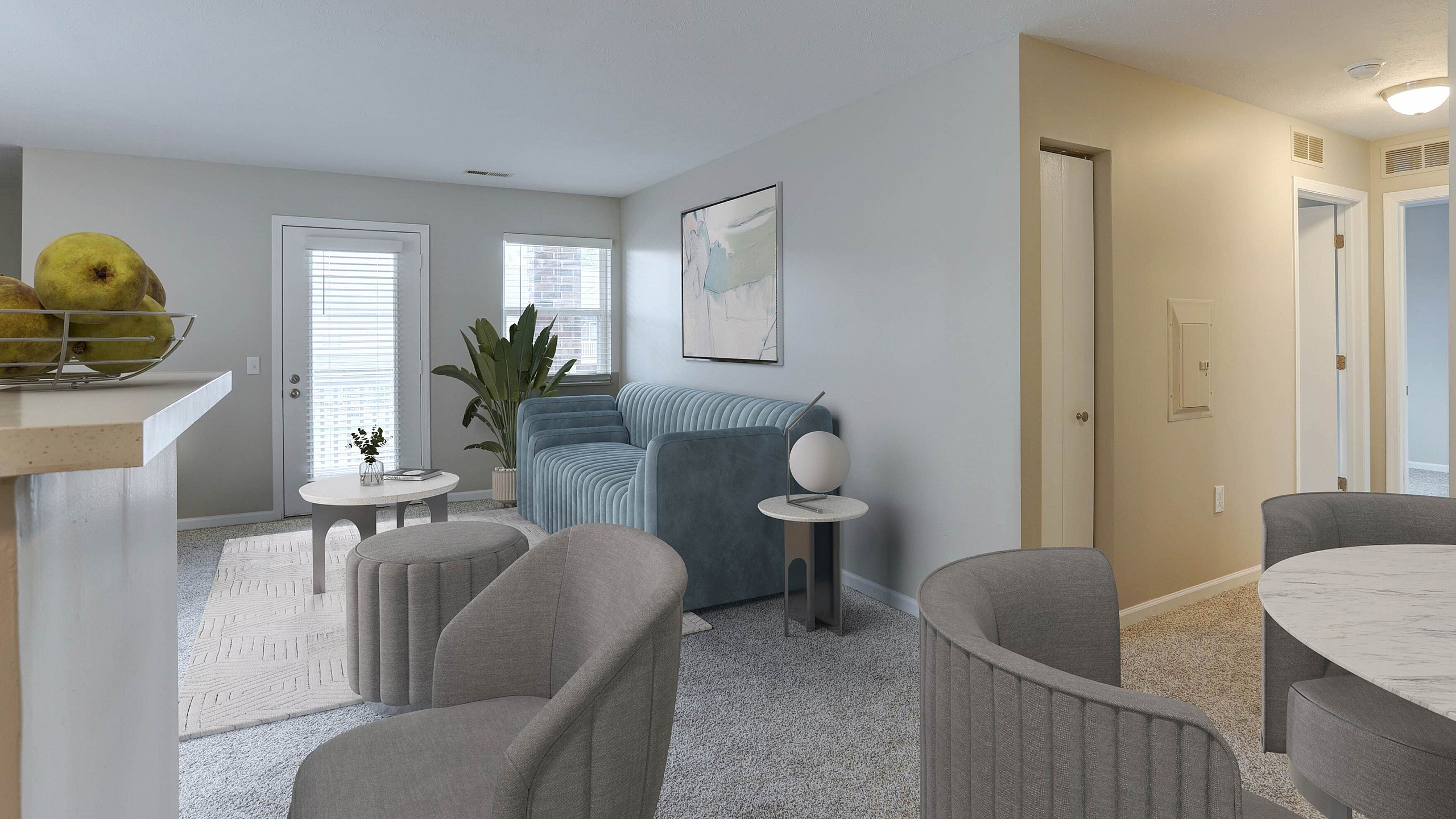 Inviting living room with modern decor, featuring a plush blue sofa, elegant gray chairs, and a cozy carpet, complemented by natural light and stylish art.