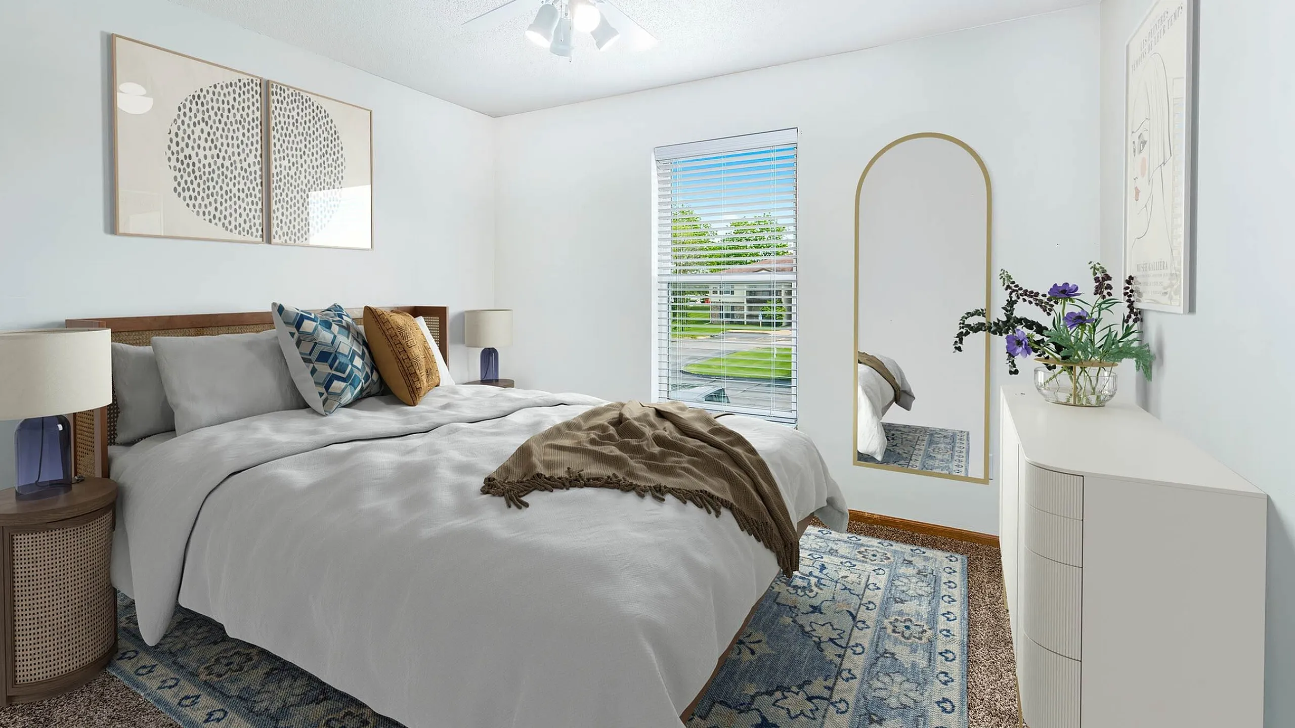 Bright and inviting bedroom with a plush bed, stylish decor, and ample natural light through a scenic window view.