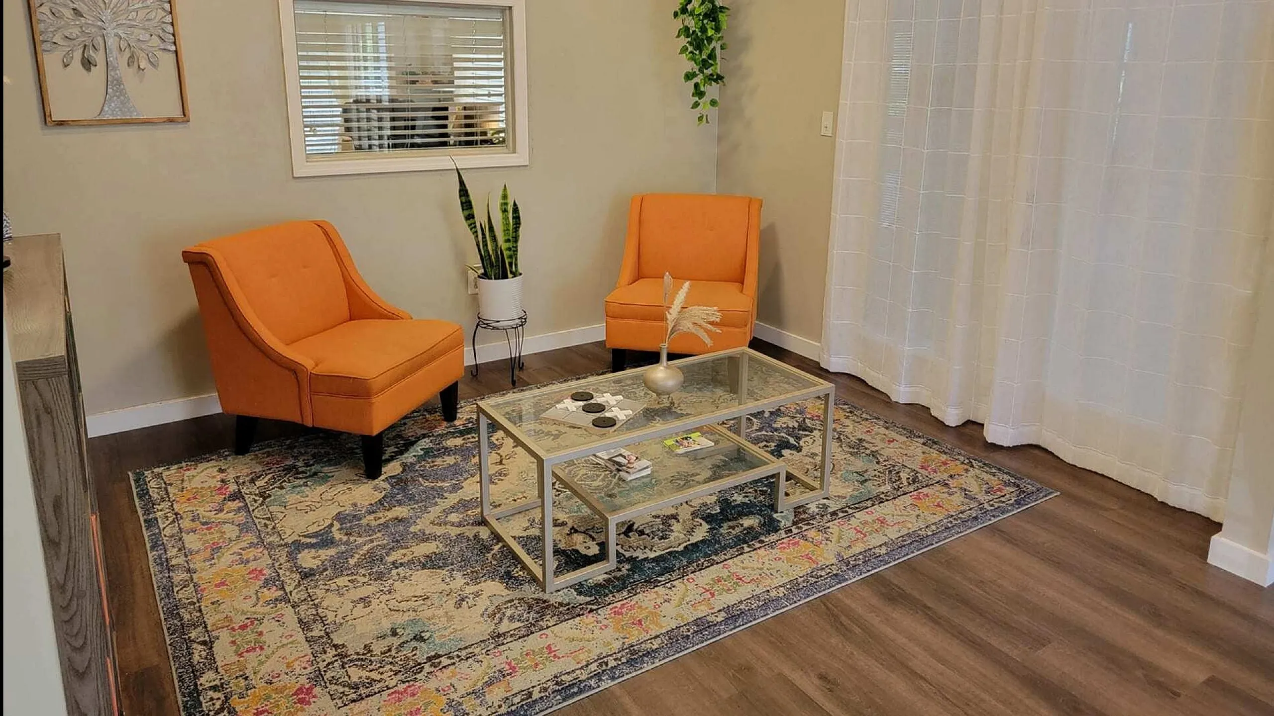 Inviting living room with vibrant orange chairs, modern decor, and natural light enhancing a cozy atmosphere.