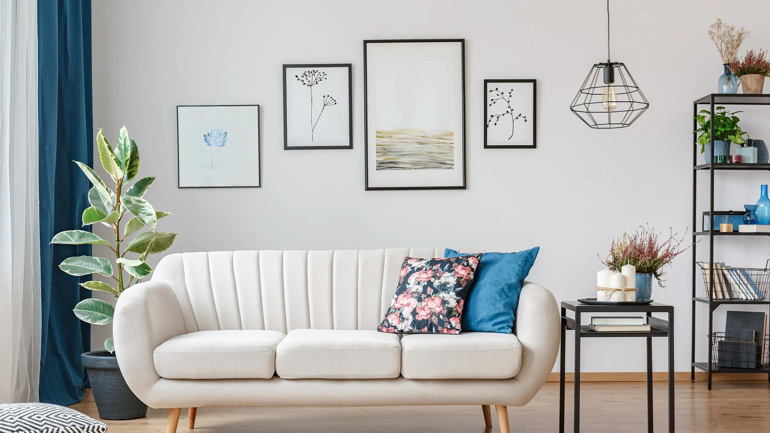 Contemporary living room with elegant white sofa, vibrant pillows, stylish artwork, and modern shelving, creating a cozy and inviting ambiance.