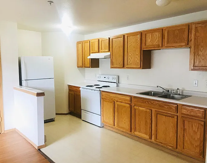 Inviting kitchen with warm wooden cabinetry, modern appliances, and ample counter space, ideal for culinary enthusiasts.