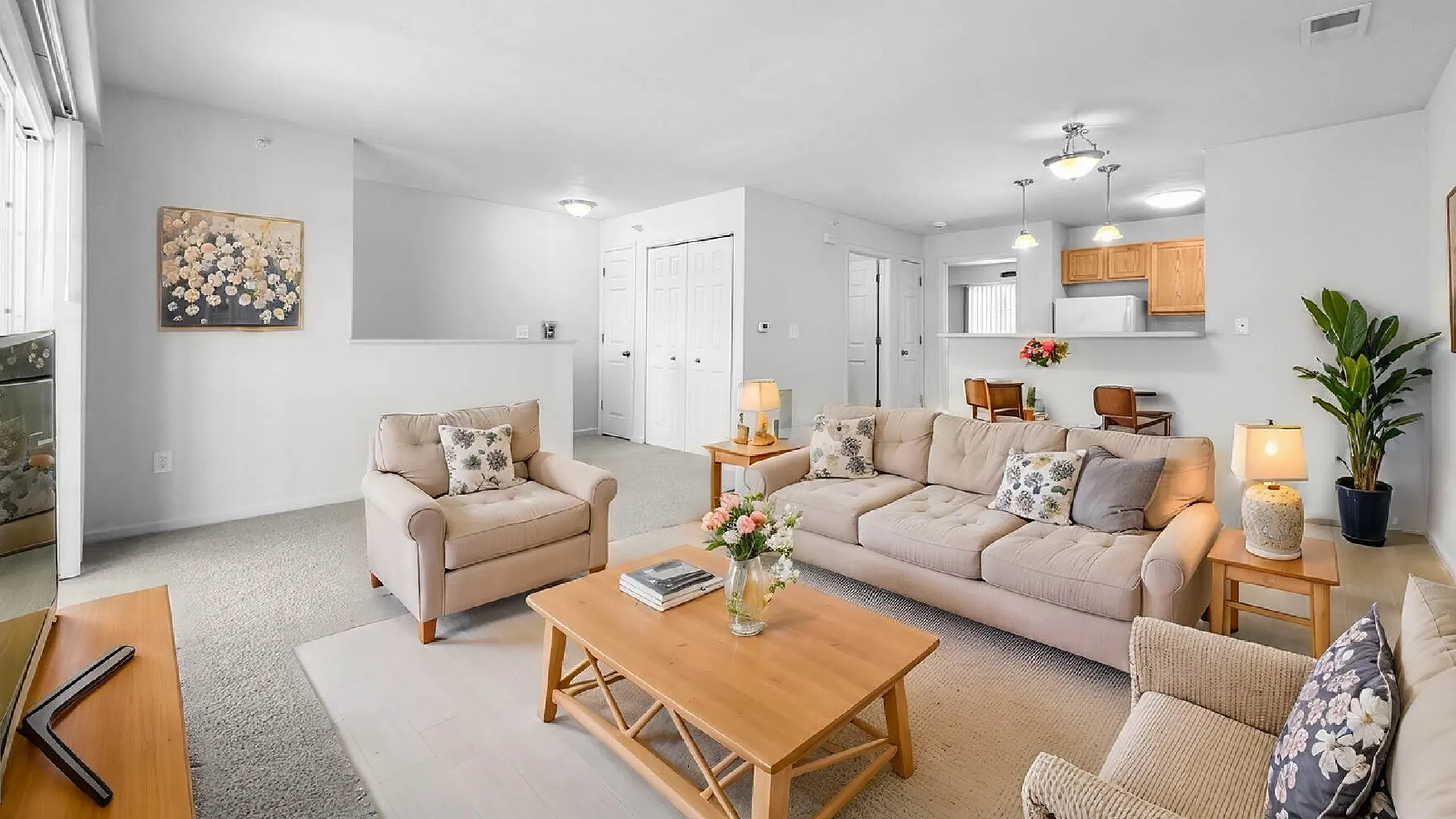 Bright and inviting living room with plush sofas, elegant decor, and open layout leading to a modern kitchen.