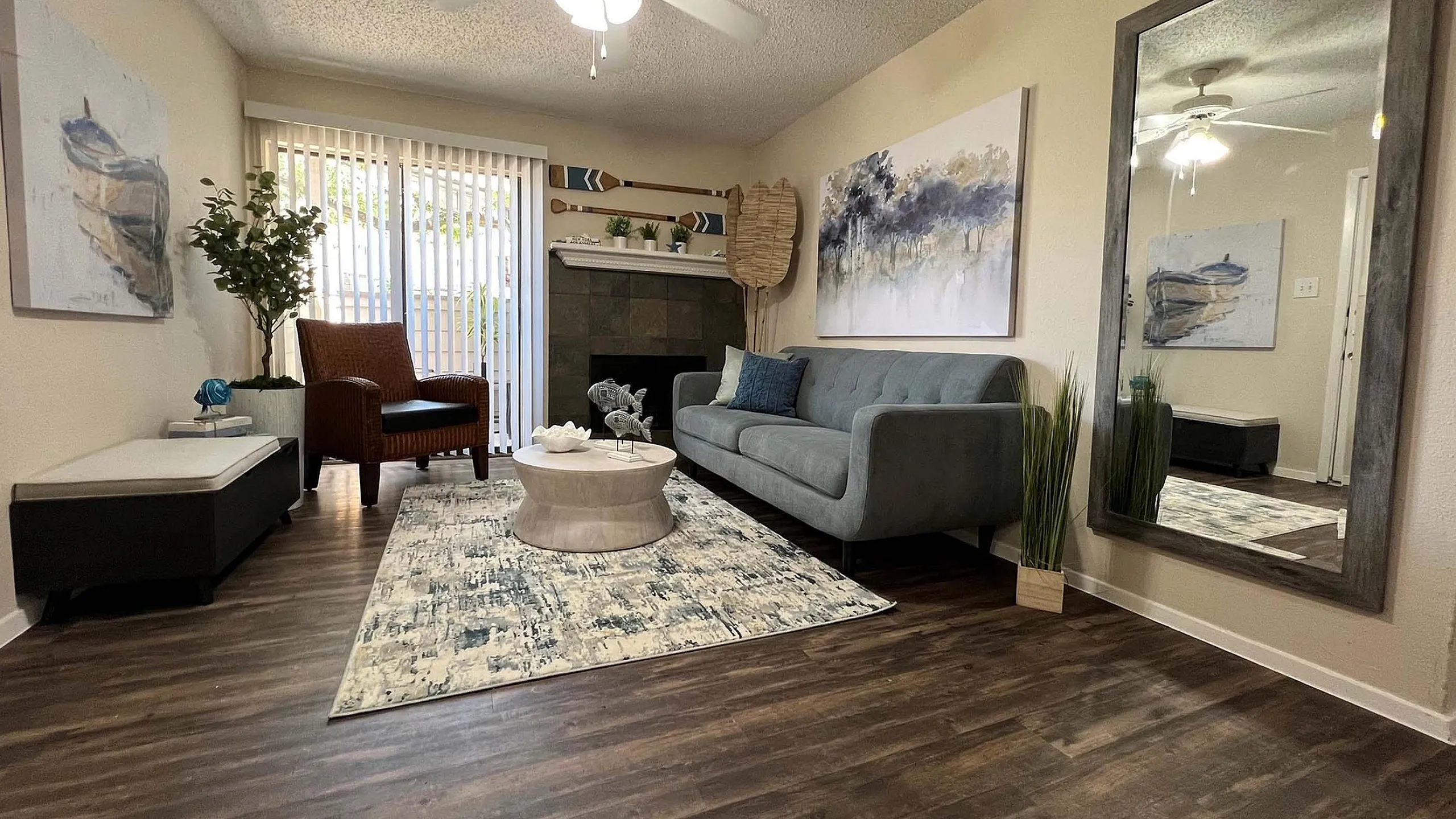 Cozy living room featuring stylish decor, a plush gray sofa, and a large mirror enhancing the space's elegance and charm.