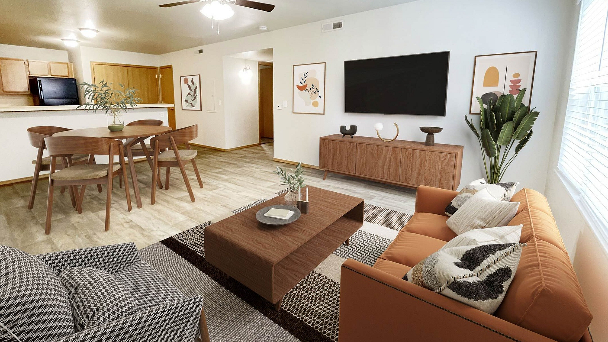 Bright and welcoming open-concept living and dining area with modern decor, featuring a stylish wood table, cozy orange sofa, and large flat-screen TV.