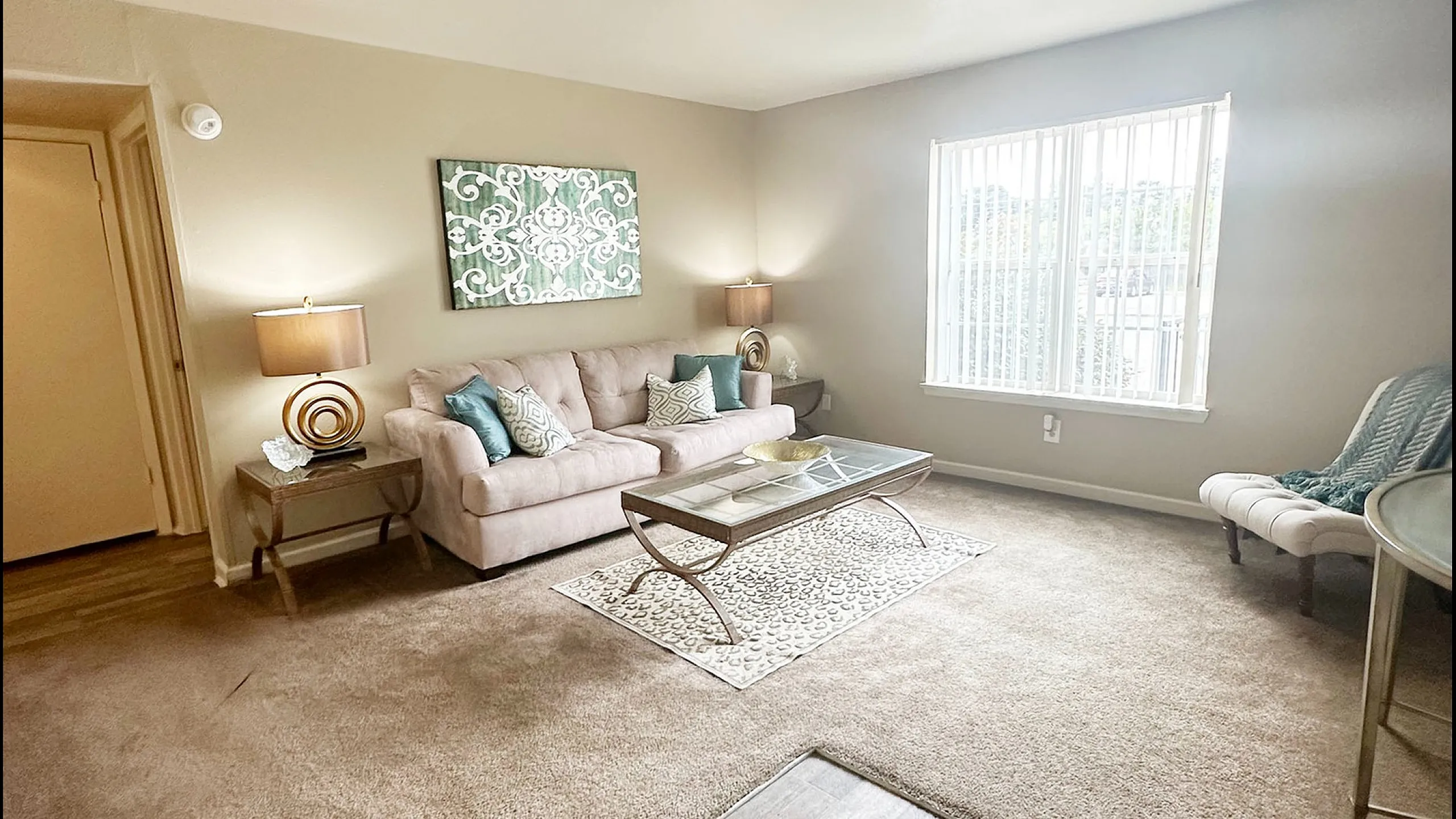 Inviting living room with plush carpeting, cozy seating, stylish decor, and abundant natural light.