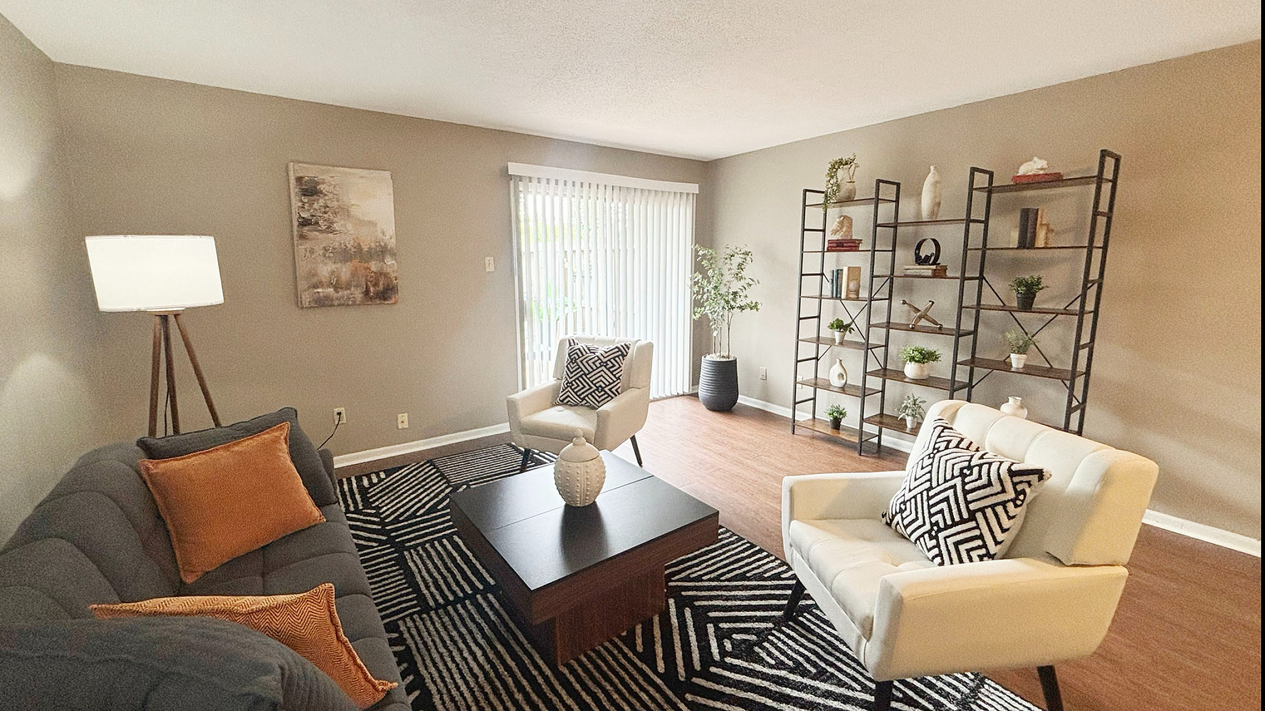 Chic living room with modern decor, featuring elegant furniture, stylish shelving, and abundant natural light from large windows.