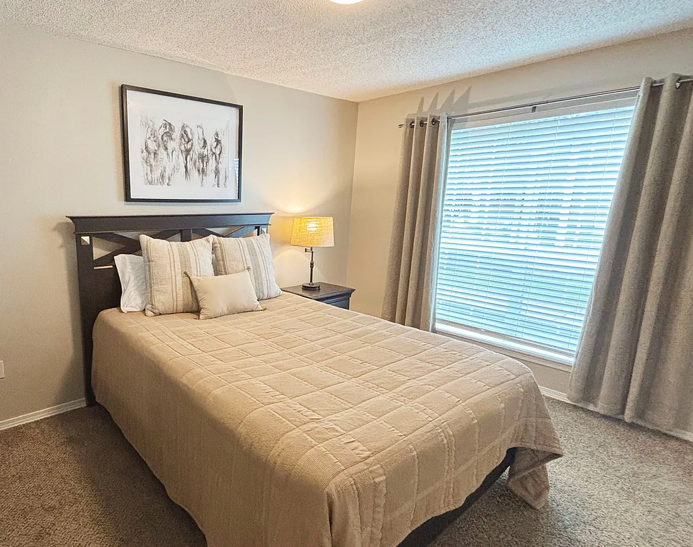 Cozy bedroom with a plush bed, elegant decor, and abundant natural light through large windows.
