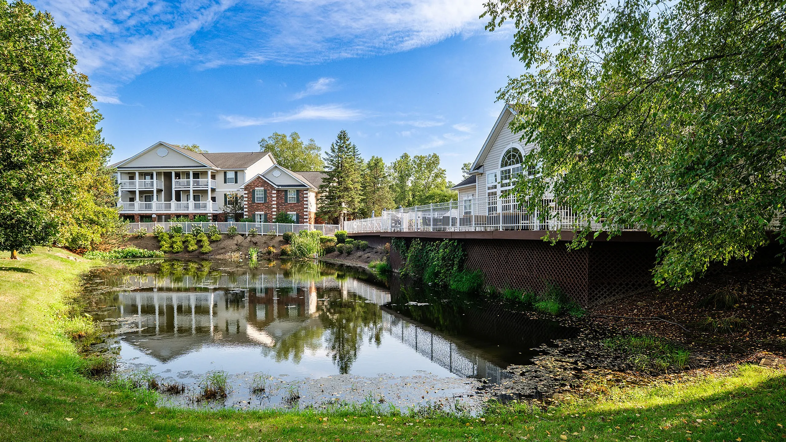 Charming residential complex with lake views surrounded by lush greenery and a clear blue sky.