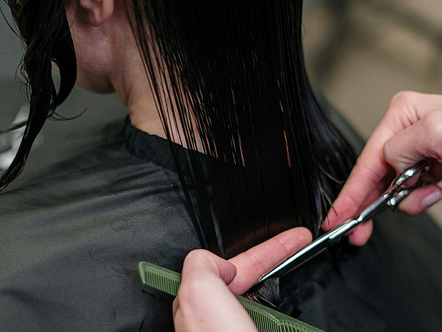 Close-up of professional hair stylist expertly cutting long, sleek hair, showcasing precision and style.
