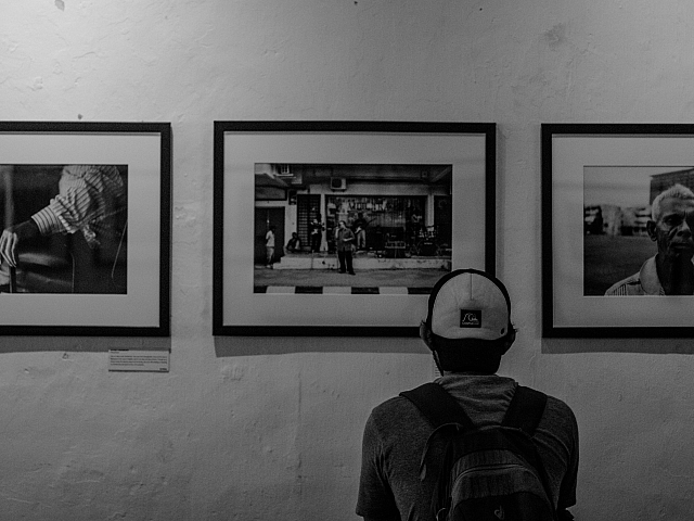 Visitor admiring a captivating exhibition of monochrome photographs, capturing street life and human expression.