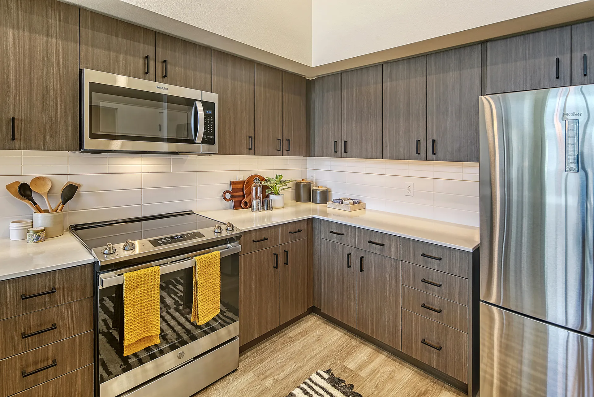 Modern kitchen with sleek dark wood cabinetry, stainless steel appliances, and elegant white countertops, perfect for stylish culinary experiences.