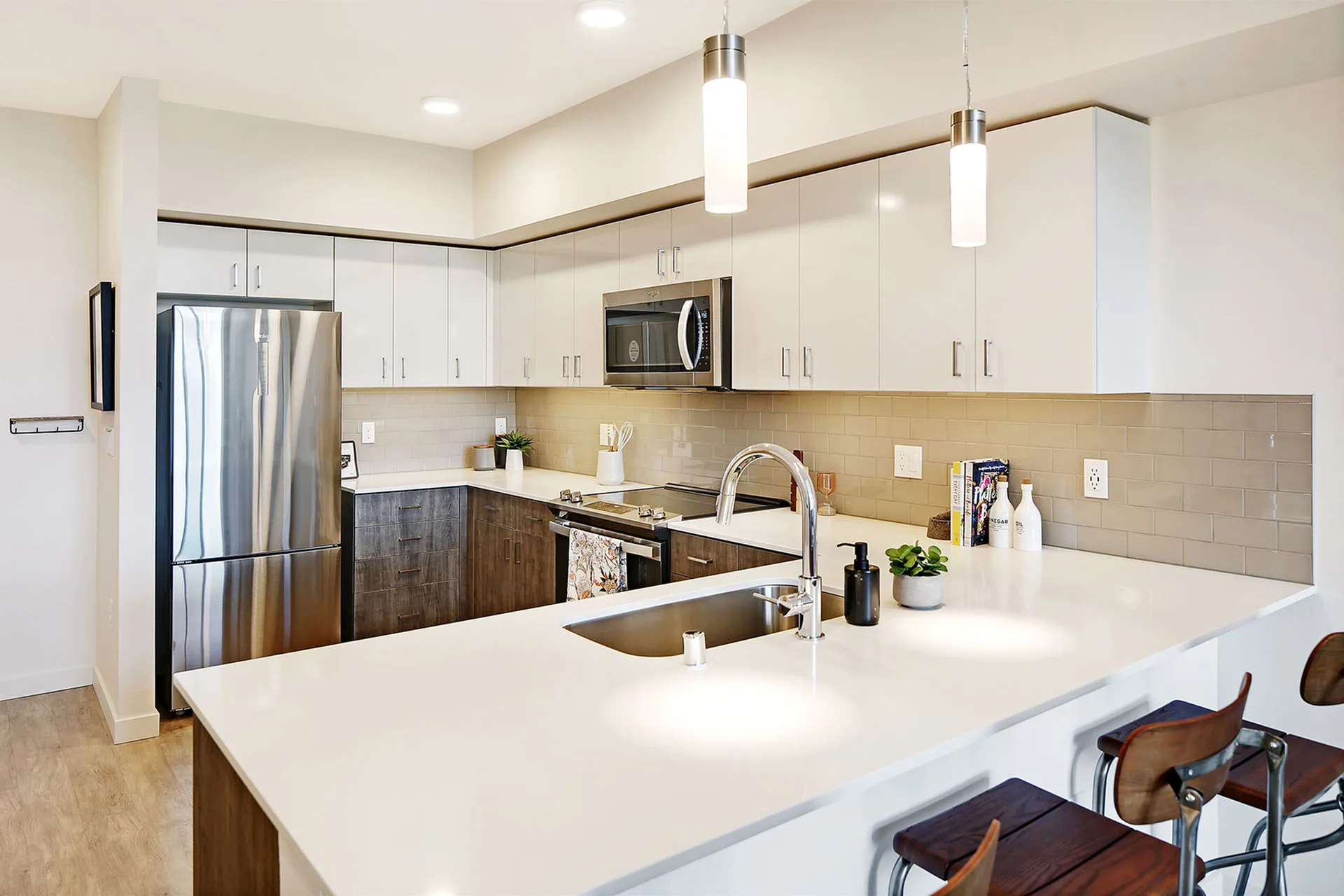 Modern kitchen with sleek white countertops, stainless steel appliances, and chic pendant lighting. Perfect for entertaining and gourmet cooking.