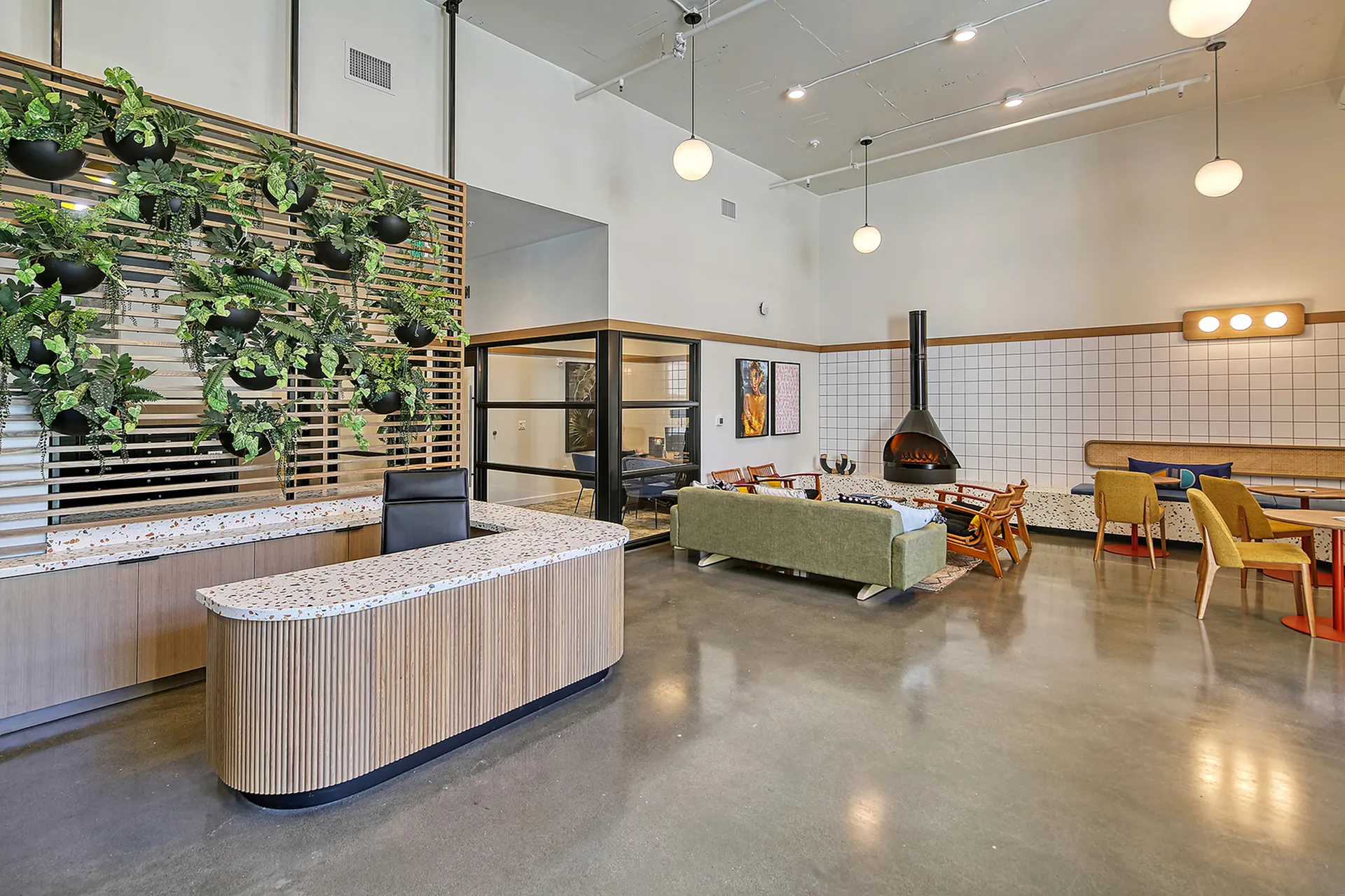 Chic modern lobby with lush green wall, sleek reception desk, cozy seating area, and modern fireplace. Ideal for welcoming guests.