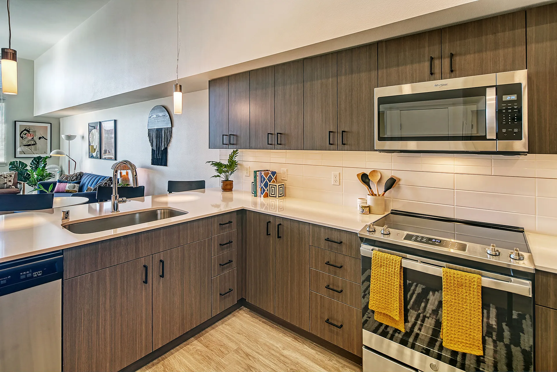 Modern kitchen with sleek cabinetry, stainless steel appliances, and an island overlooking a stylish living area with vibrant decor.
