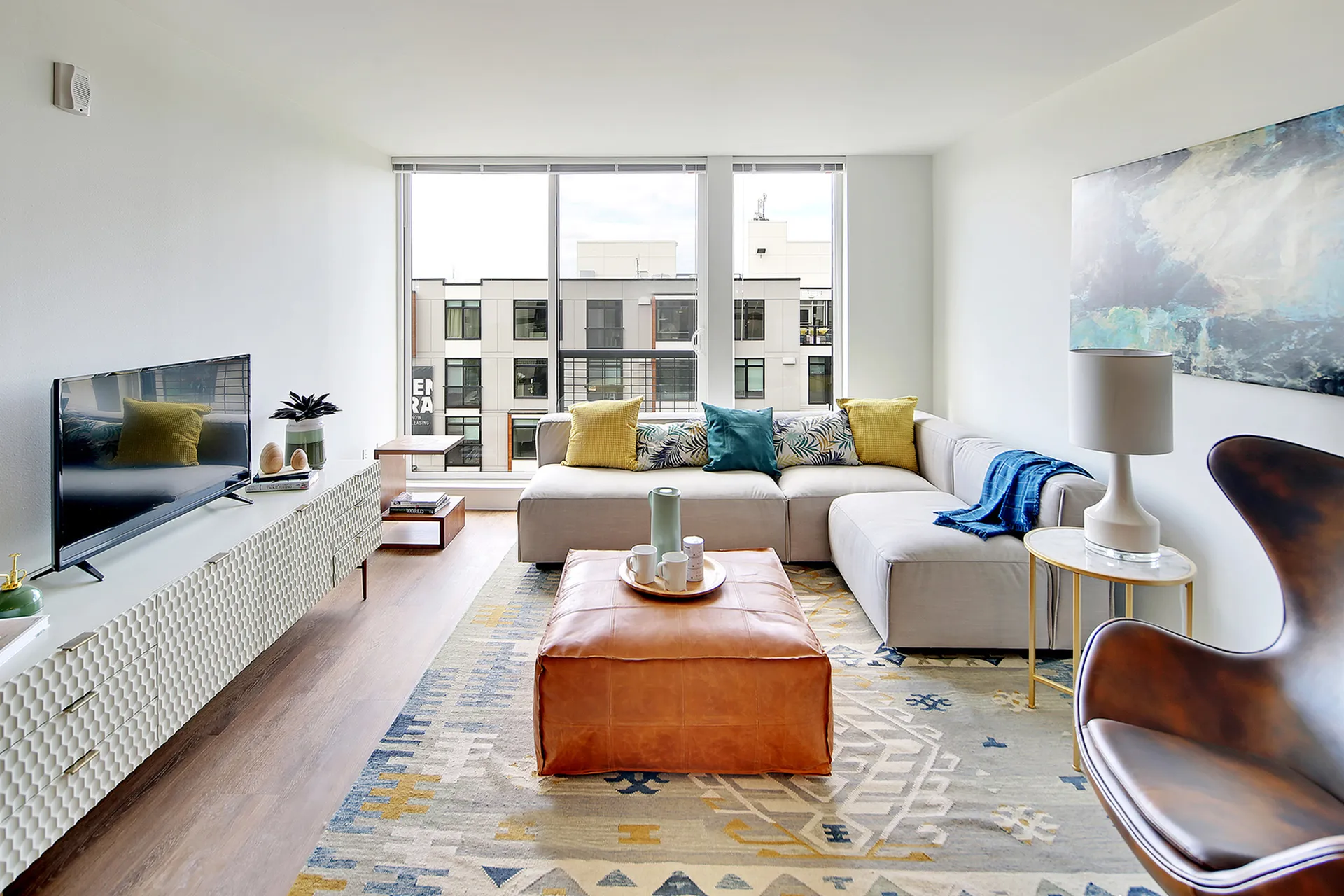 Bright and inviting living room with stylish decor, modern furniture, and large windows offering urban views.